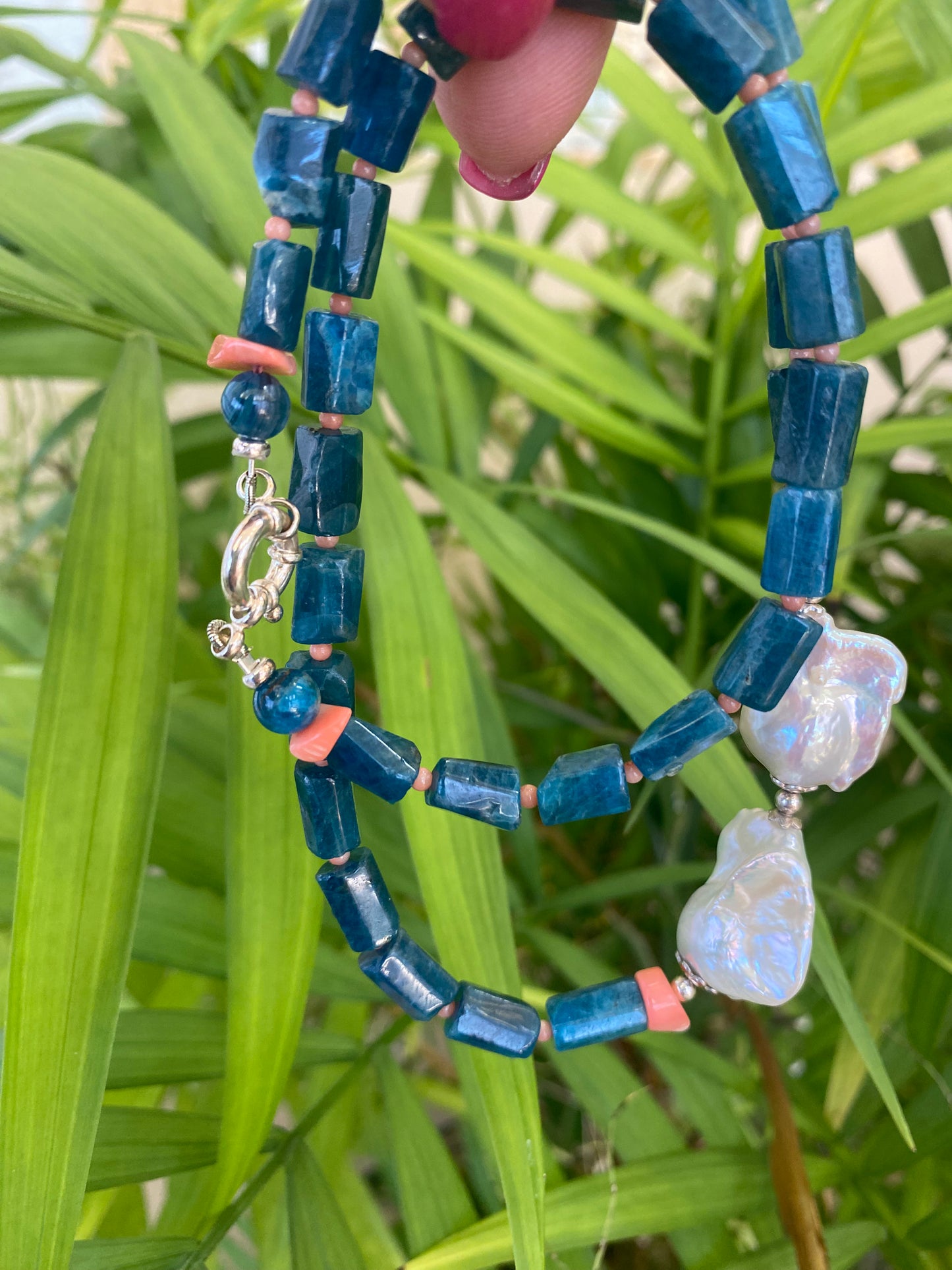 Blue apatite coral pearl necklace displayed against green leaves — natural light photo of handcrafted gemstone and pearl jewelry