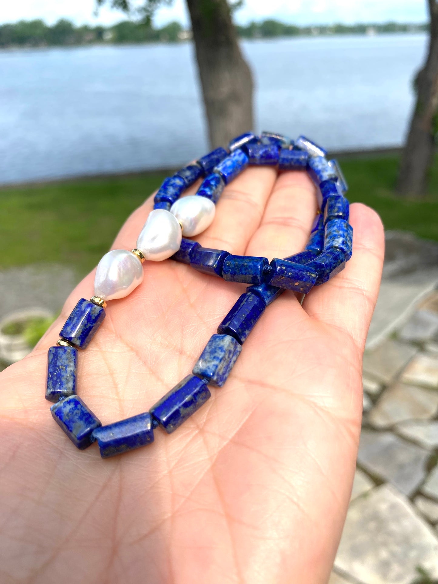 Lapis lazuli pearl necklace held in hand showing tube beads and pearl accents, handmade Canadian jewelry