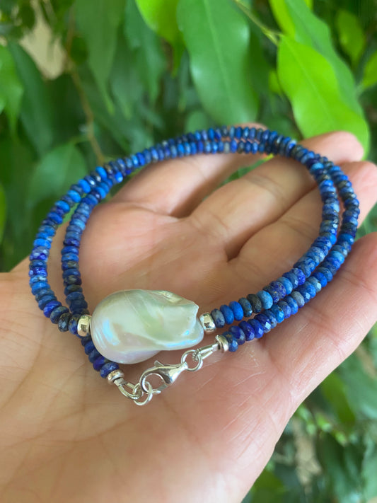 Lapis Lazuli Baroque Pearl Necklace with deep blue gemstone design showcased on a hand.