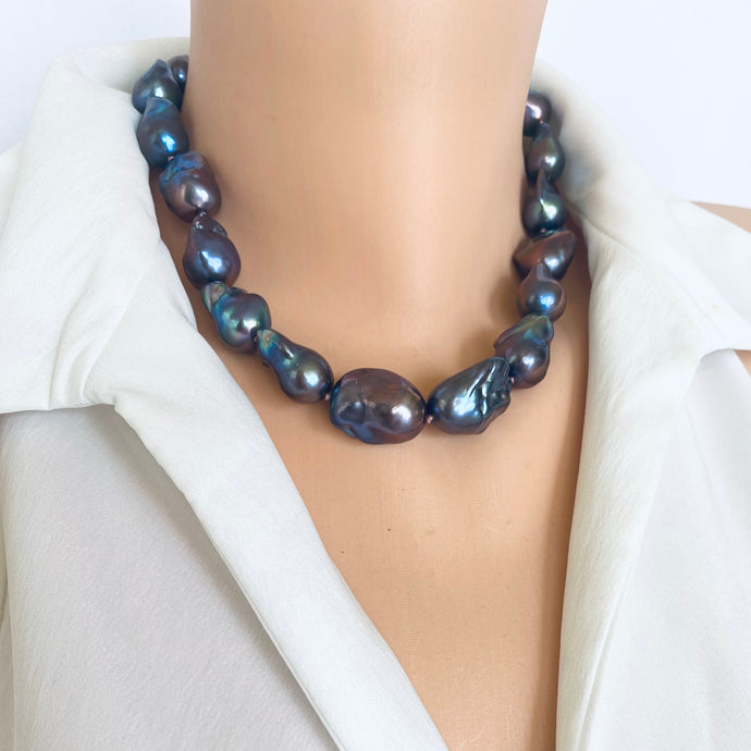 This chunky necklace features a mesmerizing peacock black baroque pearls hand knotted with a dark pink thread finished with a silver clasp