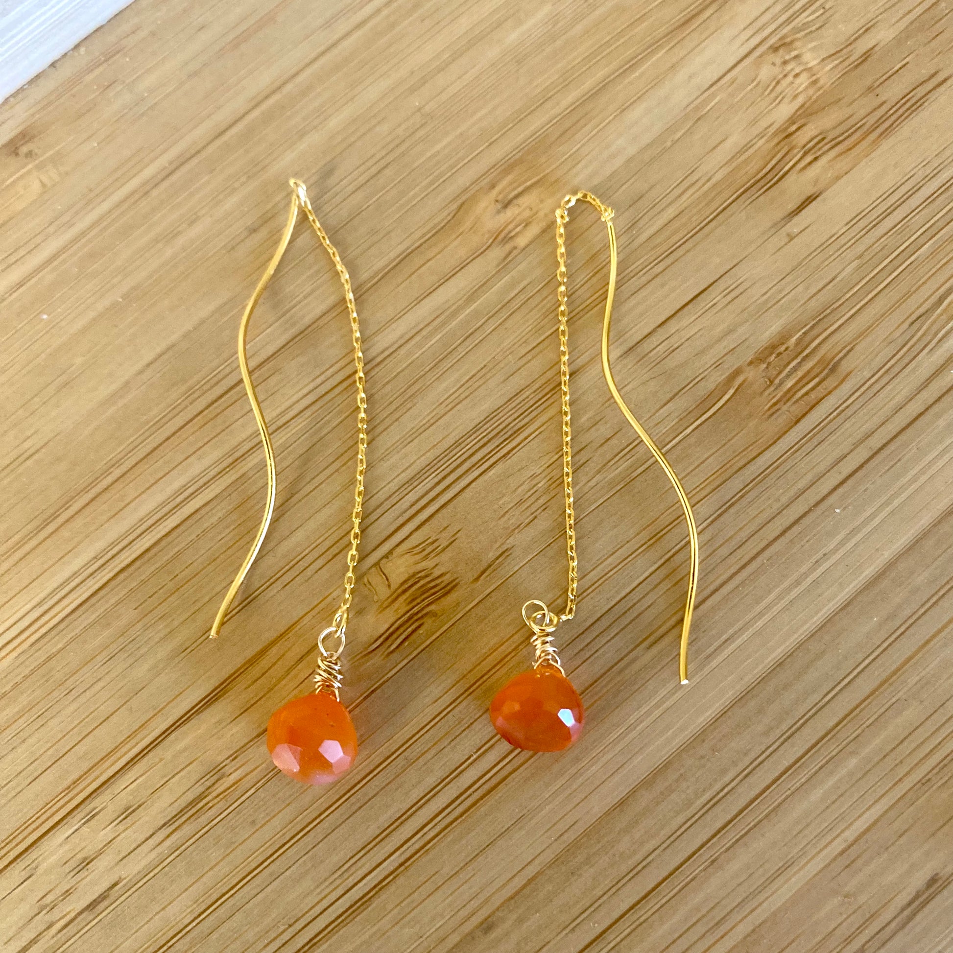 Carnelian threader earrings with vibrant orange briolettes, handmade in Canada, showcasing an elegant design.