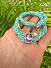 Cargar imagen en el visor de la galería, Amethyst Amazonite Choker Necklace – 8-Strand Twisted Gemstone Collar displayed on a hand with green foliage.
