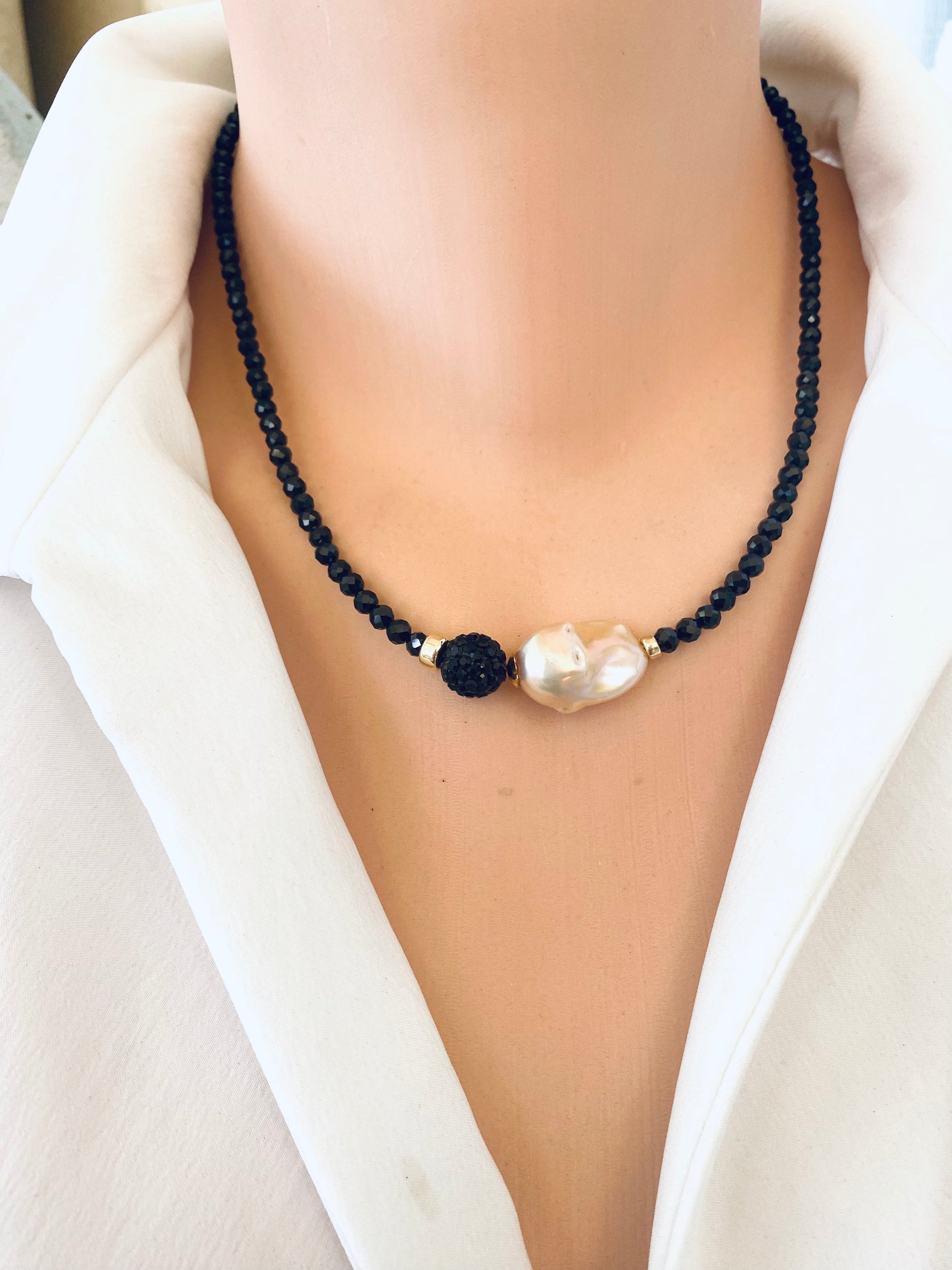 Black spinel pearl necklace on mannequin showing golden pink baroque pearl