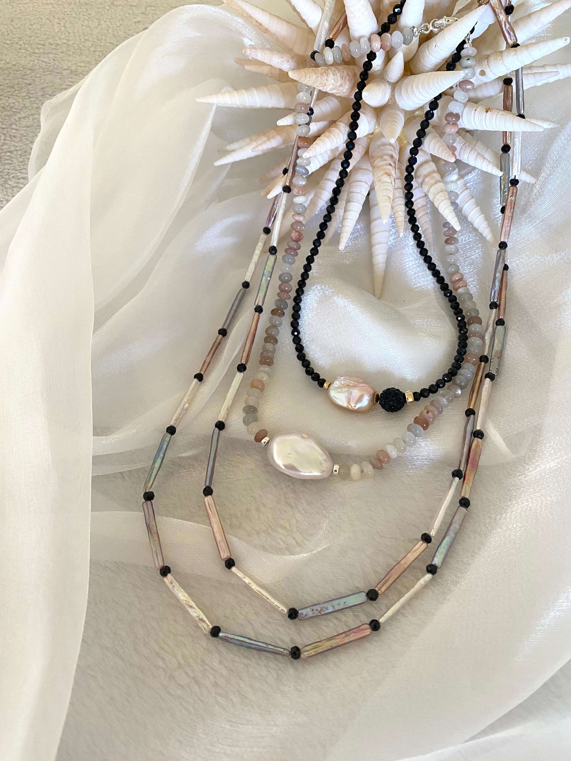Moonstone and Baroque Pearl Necklace displayed on soft fabric with seashell decor.