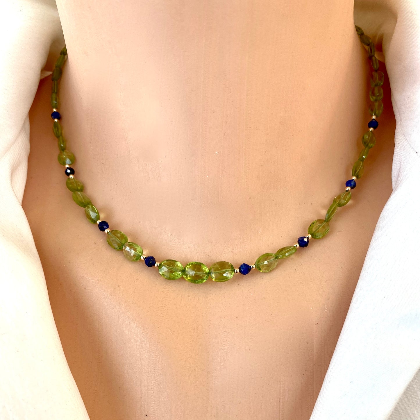 Peridot lapis necklace featuring faceted peridot oval beads and lapis lazuli accents on a model.