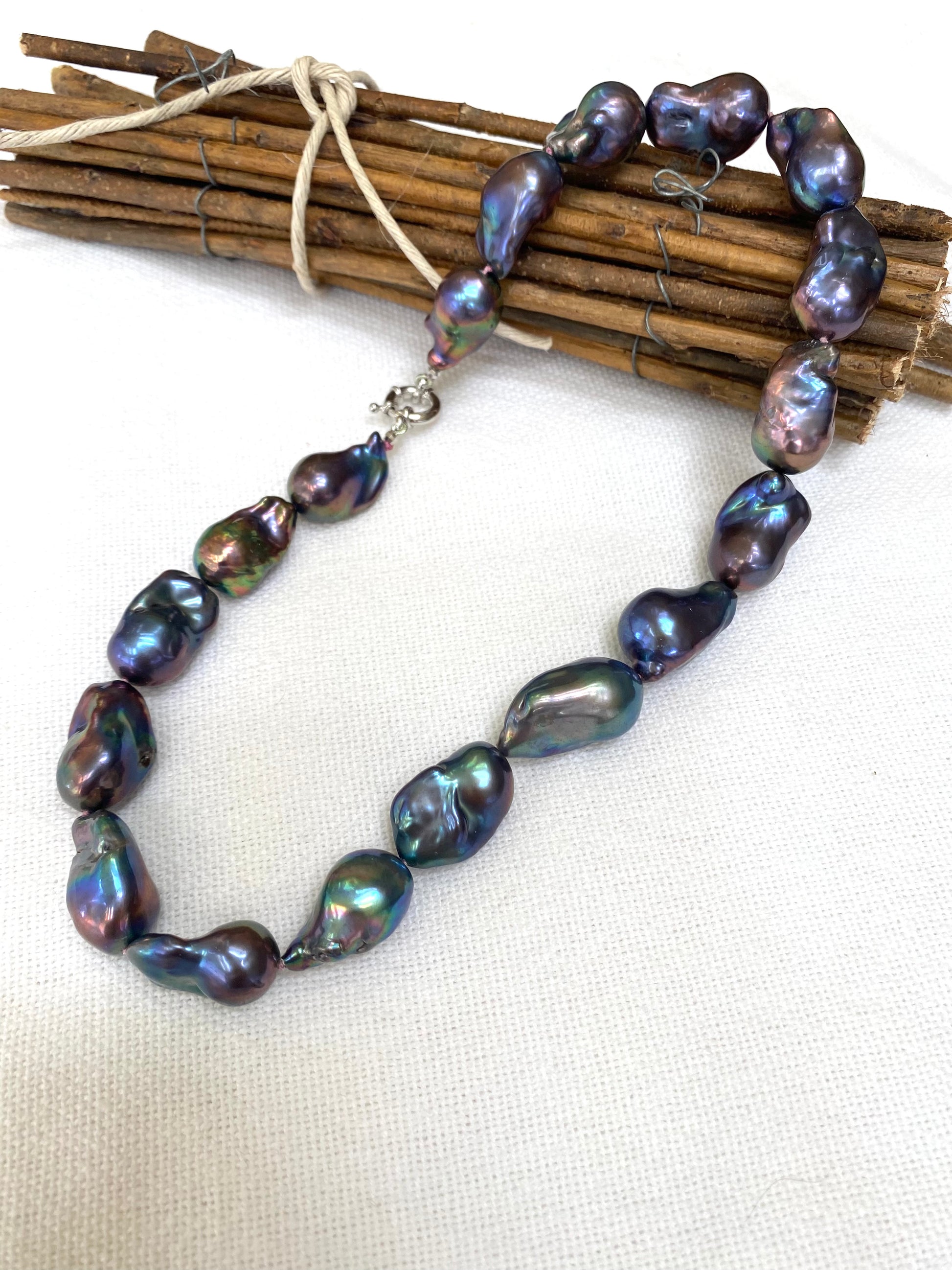 Handcrafted black baroque pearl necklace featuring unique peacock-black freshwater pearls on dark-pink silk thread.