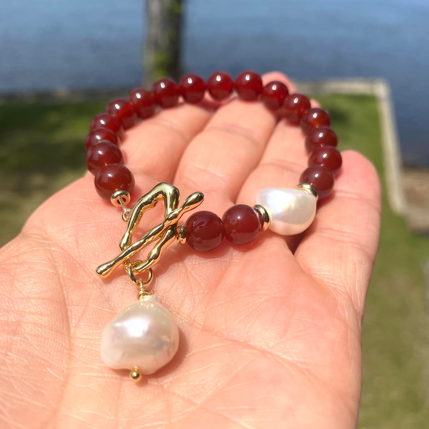Carnelian pearl bracelet featuring burnt orange carnelian beads and a white baroque pearl, showcasing a warm, earthy elegance.