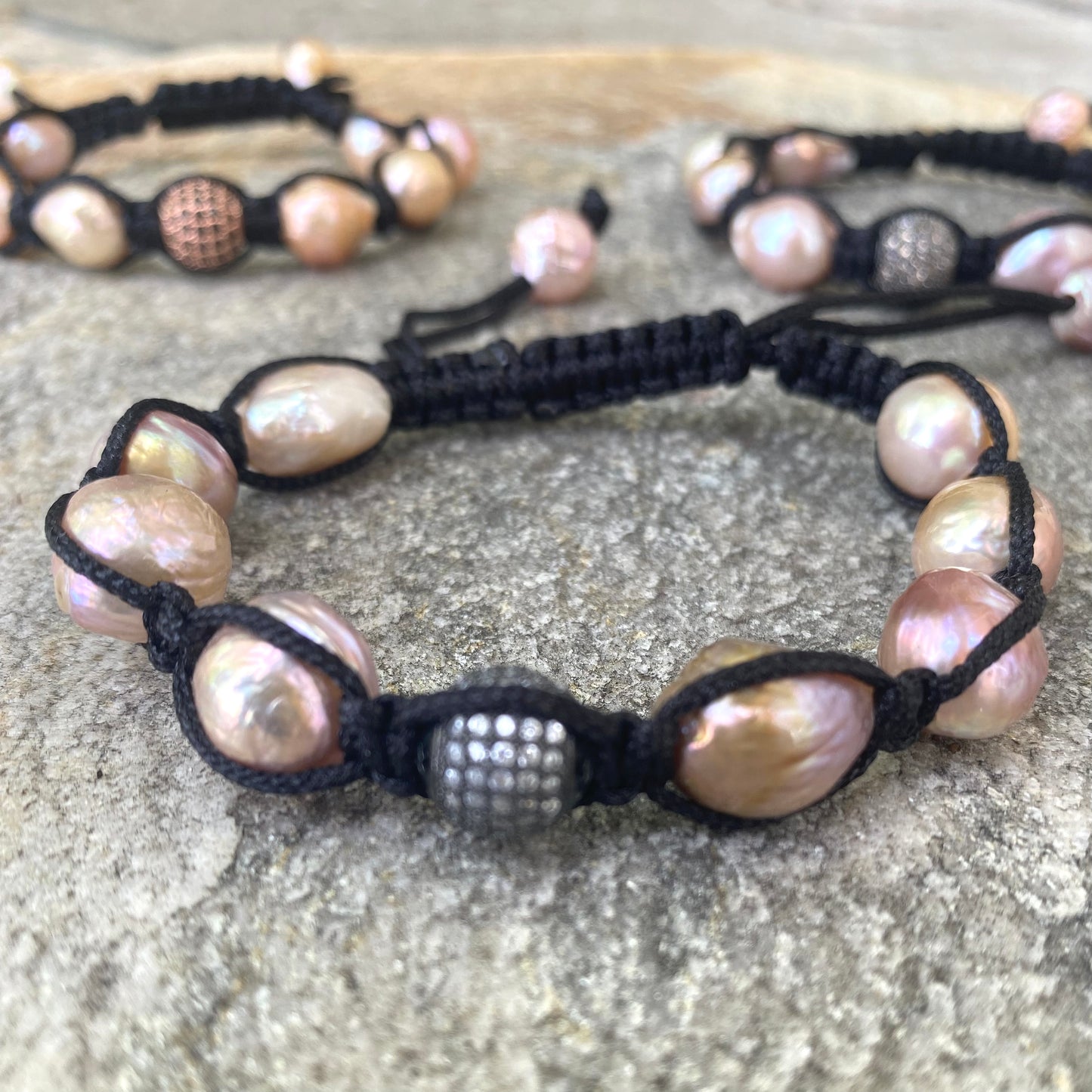 Baroque pearl bracelet featuring pastel baroque pearls on black macramé thread, showcasing organic texture and refined sparkle.