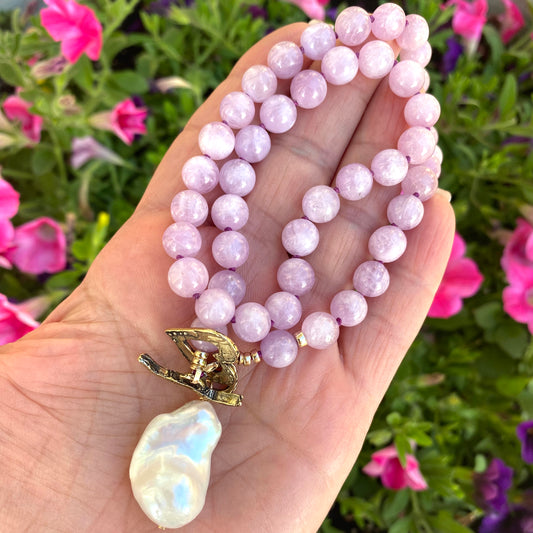 Kunzite toggle necklace with baroque pearl pendant held in hand, showcasing pink kunzite beads and elegant design.