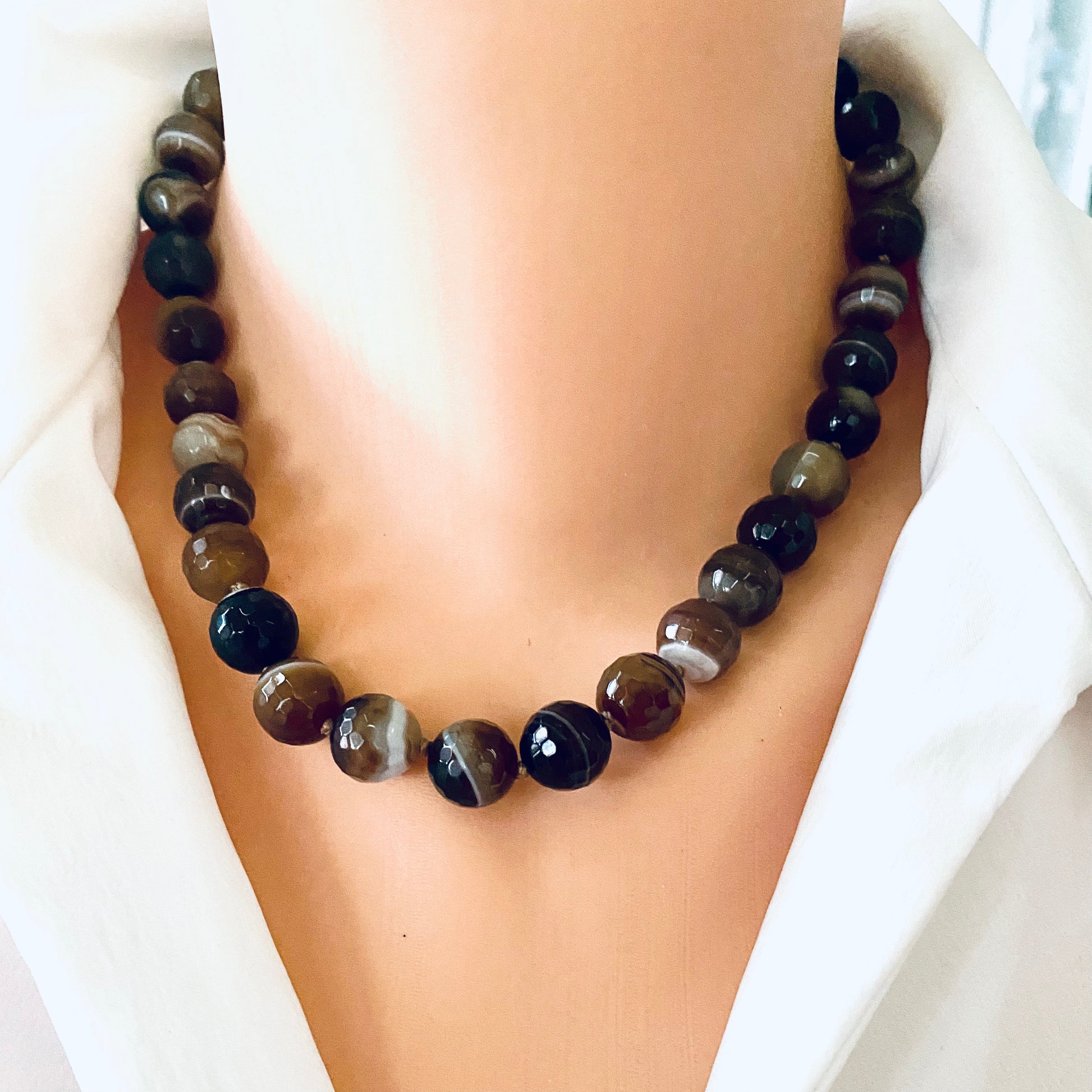 Botswana agate candy necklace with gold bronze details displayed on a mannequin's neck showcasing earthy tones.