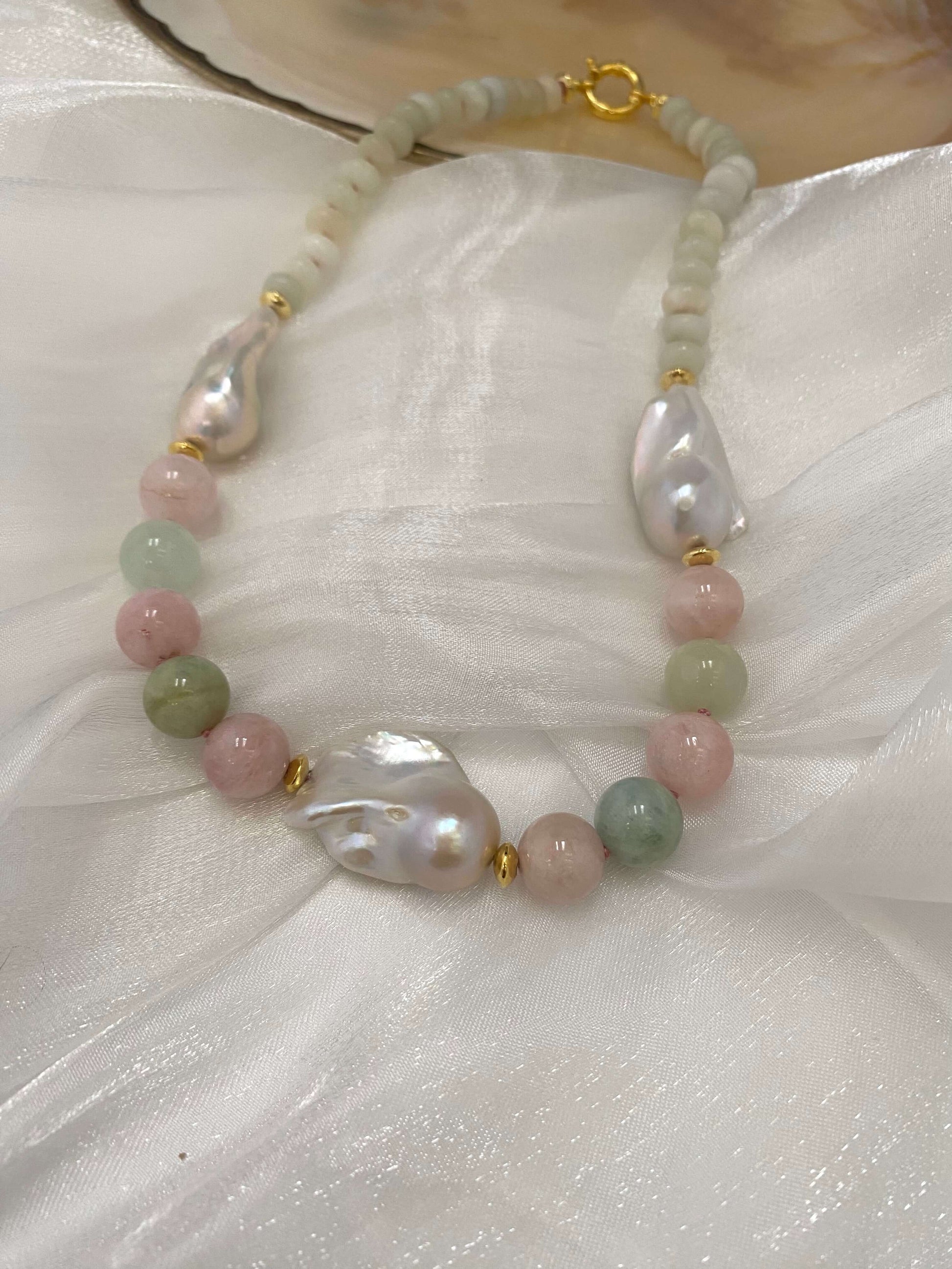 Morganite and jade necklace with baroque pearls displayed on white fabric, showing soft pink silk thread and gold vermeil clasp.