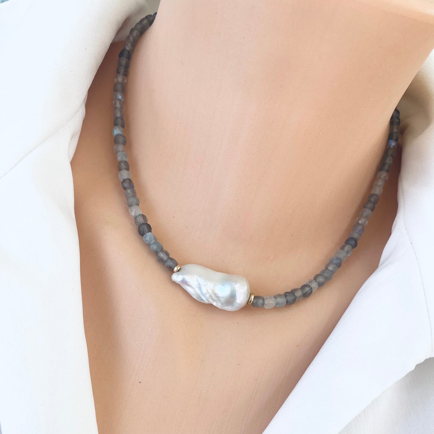 Labradorite necklace with blue flash and baroque pearl on display, showcasing elegant craftsmanship and delicate design.