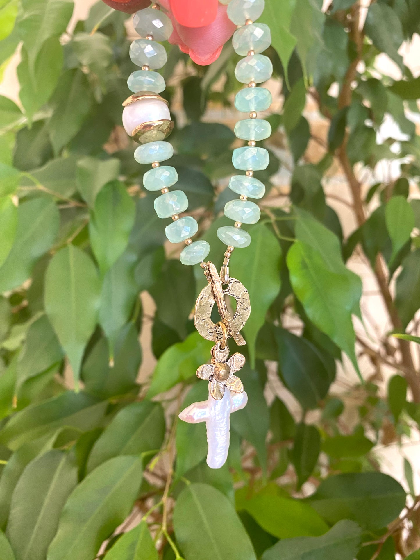 Chalcedony bracelet featuring aqua green beads, cross pearl pendant, and daisy charm, representing elegance and meaning.