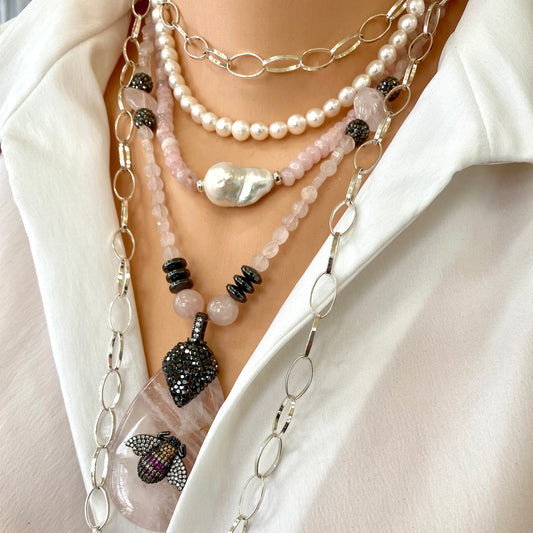 Rose quartz necklace with rhinestone pavé bee pendant and multi-layered strands with pearl and gemstone details.