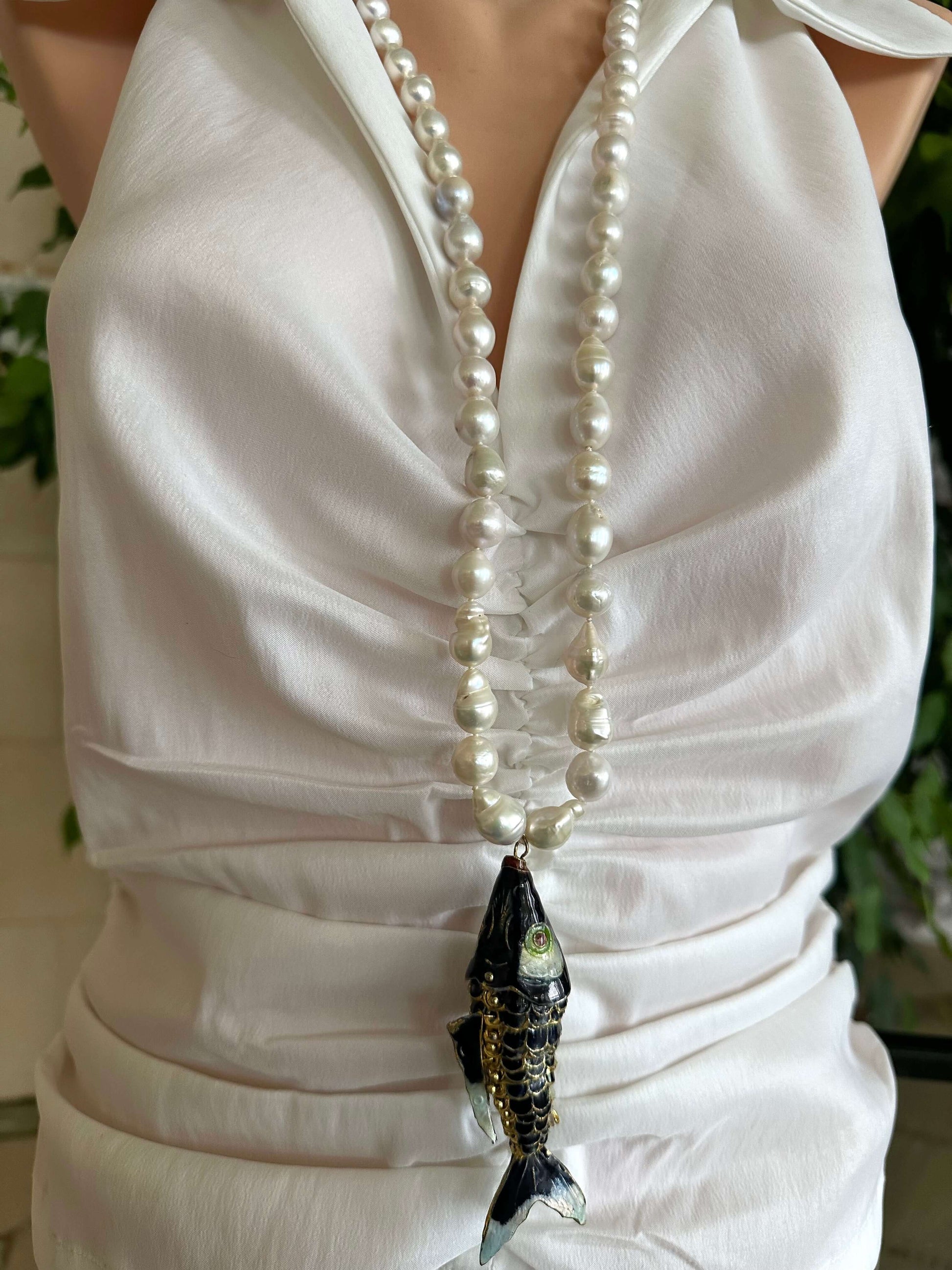 Fish pendant pearl necklace with black cloisonné fish and baroque pearls on elegant display.