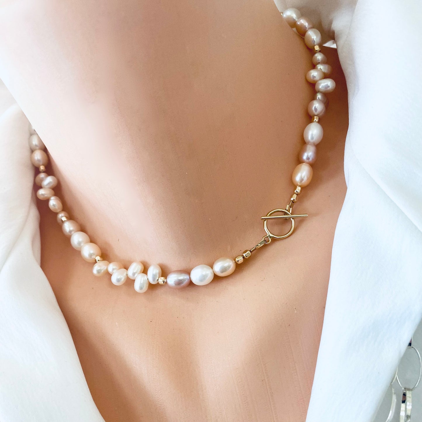 Pearl toggle necklace with pastel pearls and 14K gold filled clasp worn on a mannequin's neck.