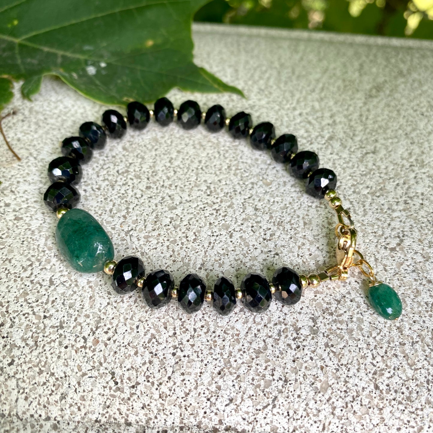 Spinel emerald bracelet featuring black spinel beads and a green emerald centerpiece, showcasing elegant craftsmanship.