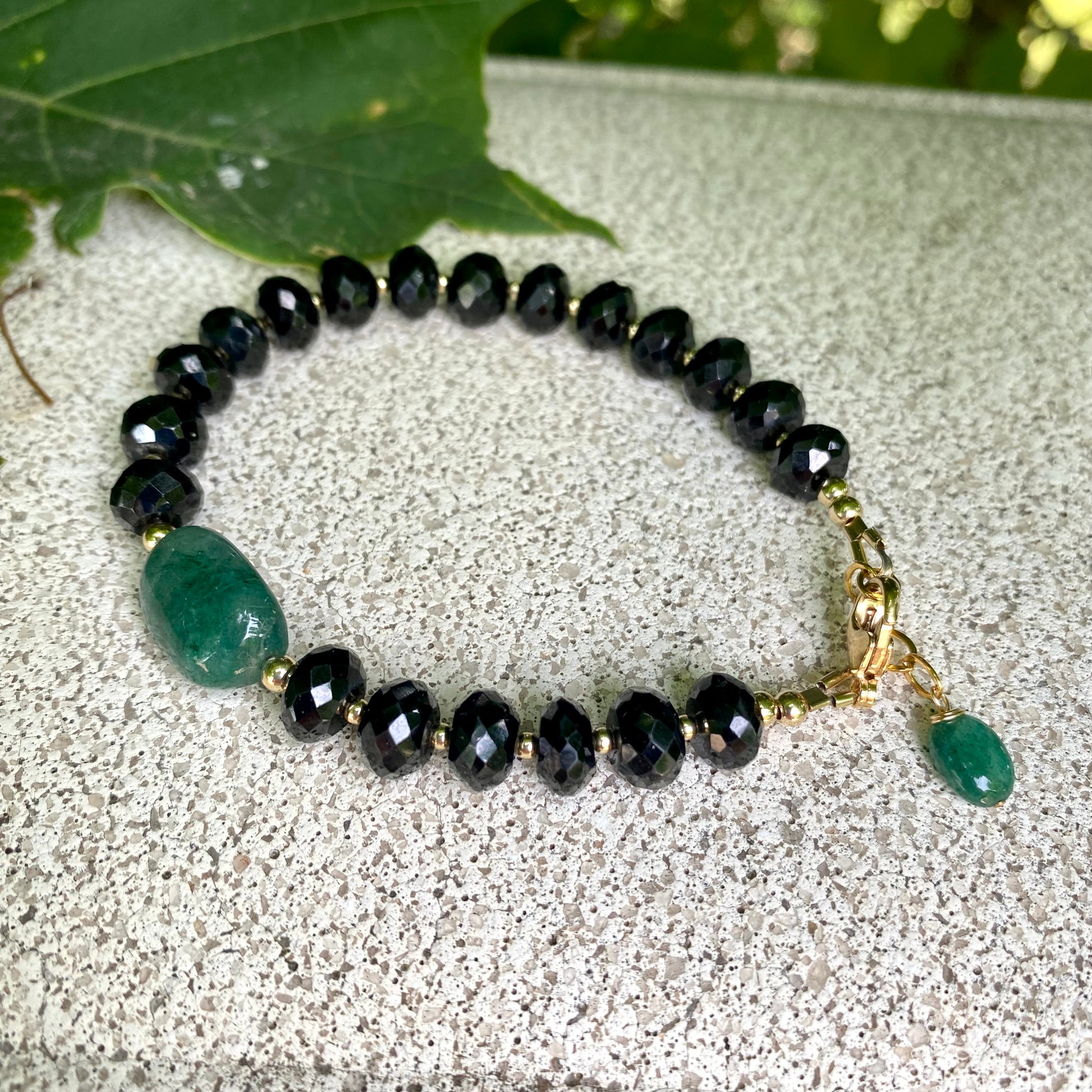 Spinel emerald bracelet featuring black spinel beads and a green emerald centerpiece, showcasing elegant craftsmanship.