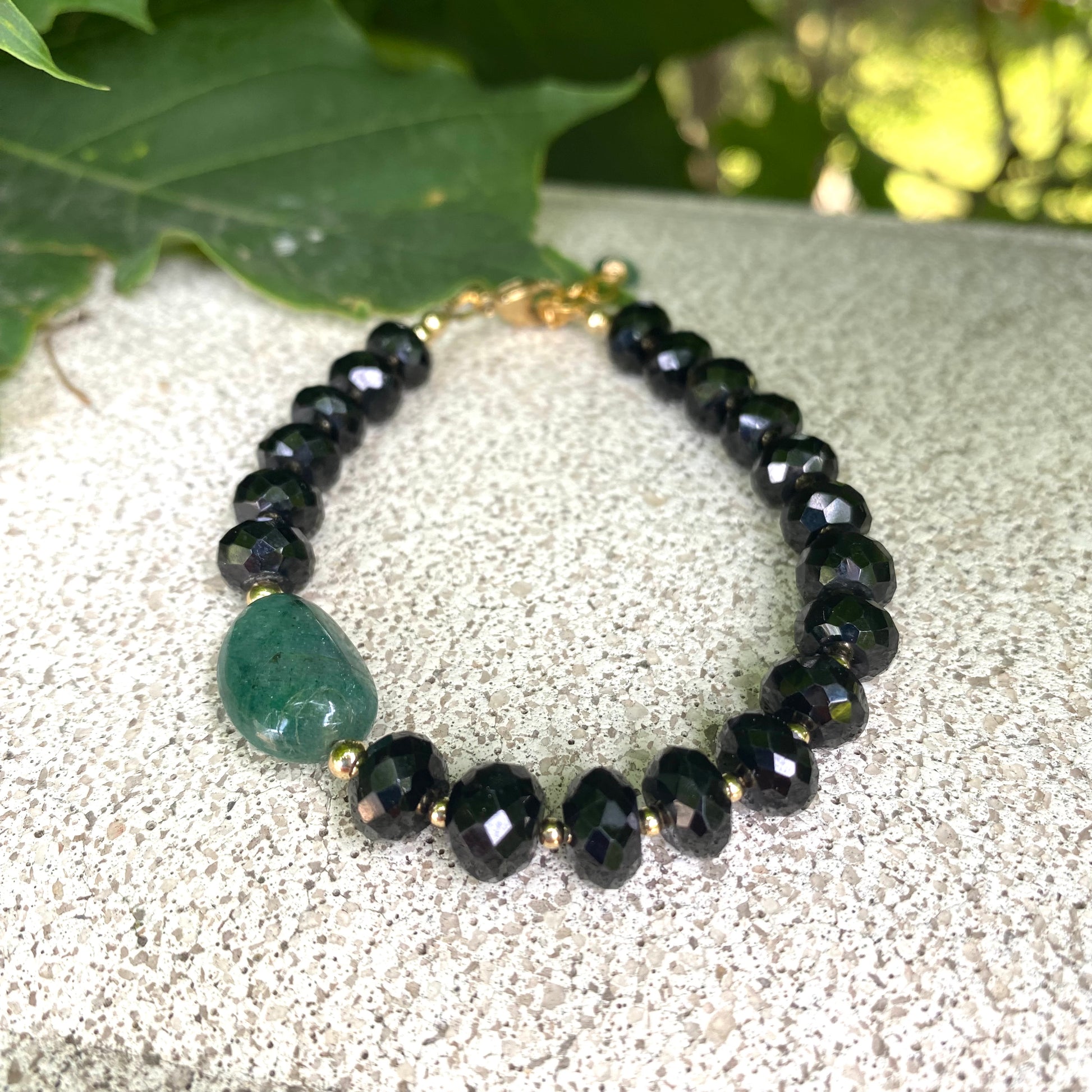 Spinel emerald bracelet featuring black spinel rondelle beads and a green emerald centerpiece.