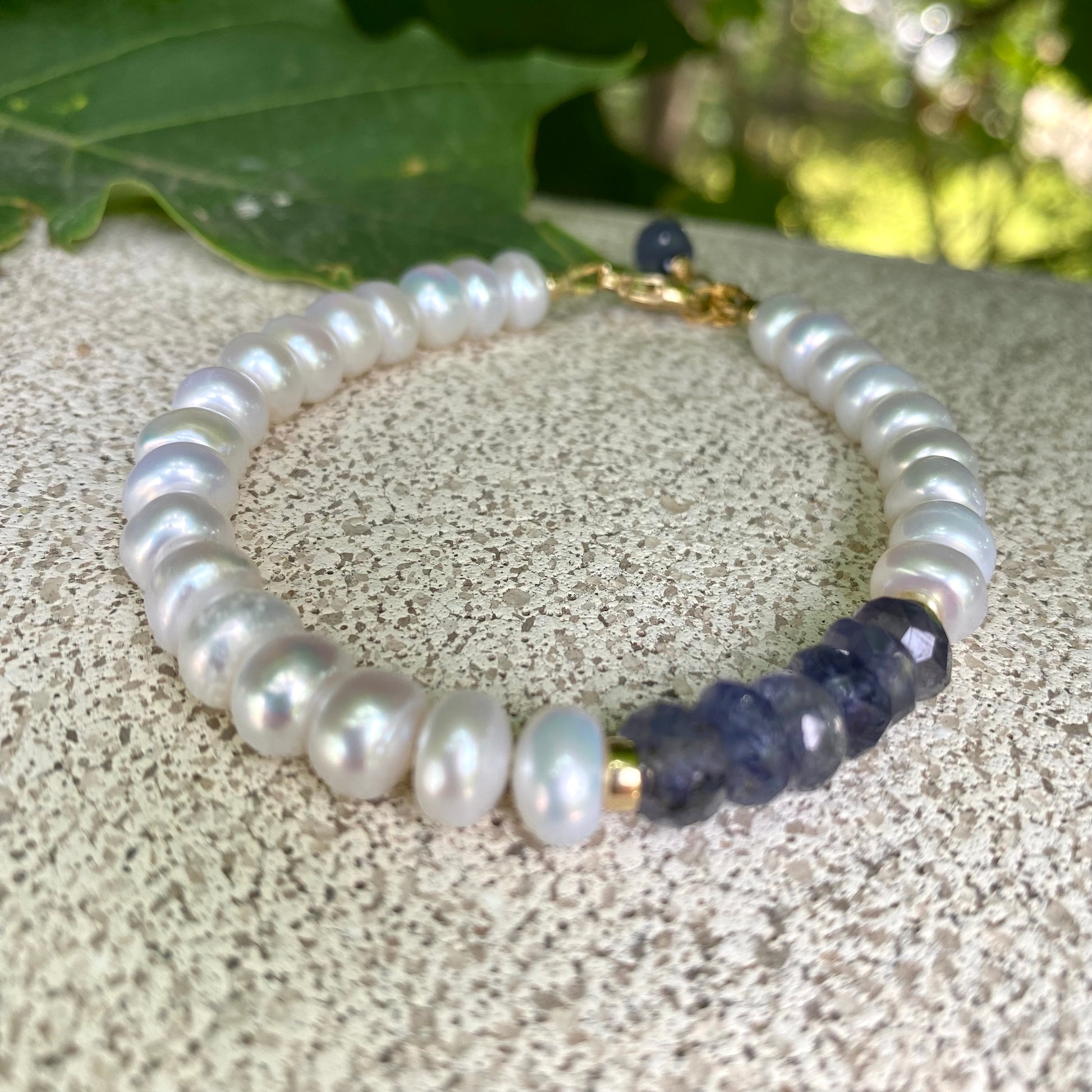Iolite pearl bracelet featuring blue iolite and luminous white pearls, showcasing elegance and craftsmanship.