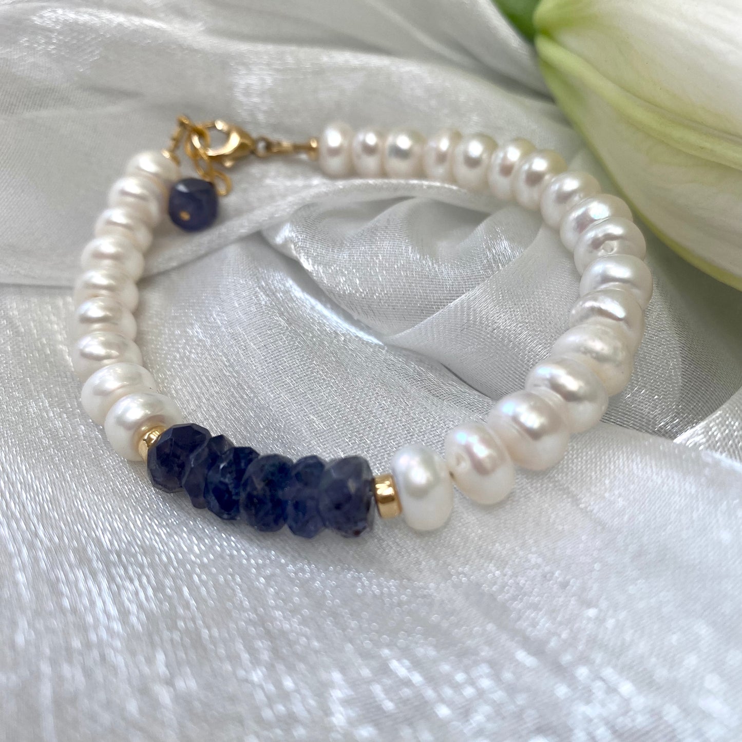 Iolite pearl bracelet featuring blue iolite rondelle beads and white pearls, showcasing elegance and color.