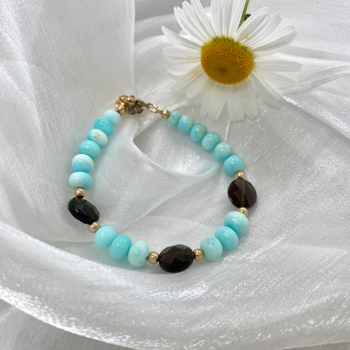 Opal quartz bracelet featuring sky blue opal and smoky quartz beads, elegantly displayed with a white daisy.