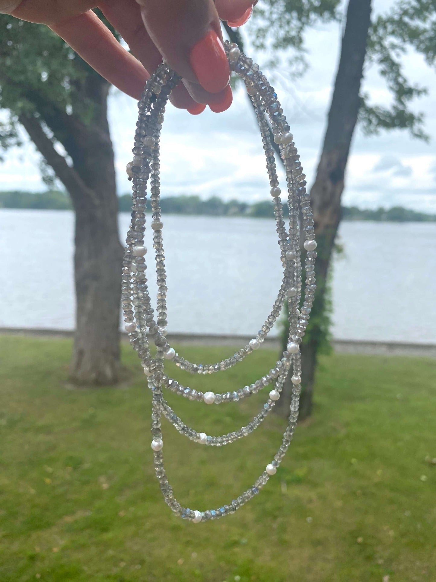 Labradorite freshwater pearl necklace displayed outdoors by a lake, showcasing its handcrafted, long design with beads.