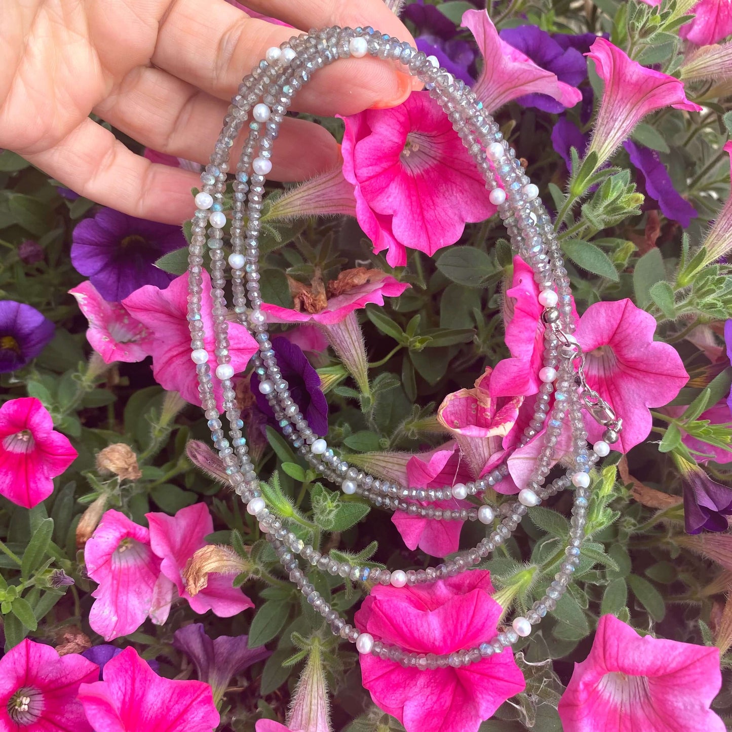 Labradorite freshwater pearl necklace displayed against vibrant pink flowers, showcasing handcrafted long design with shimmering gemstones.