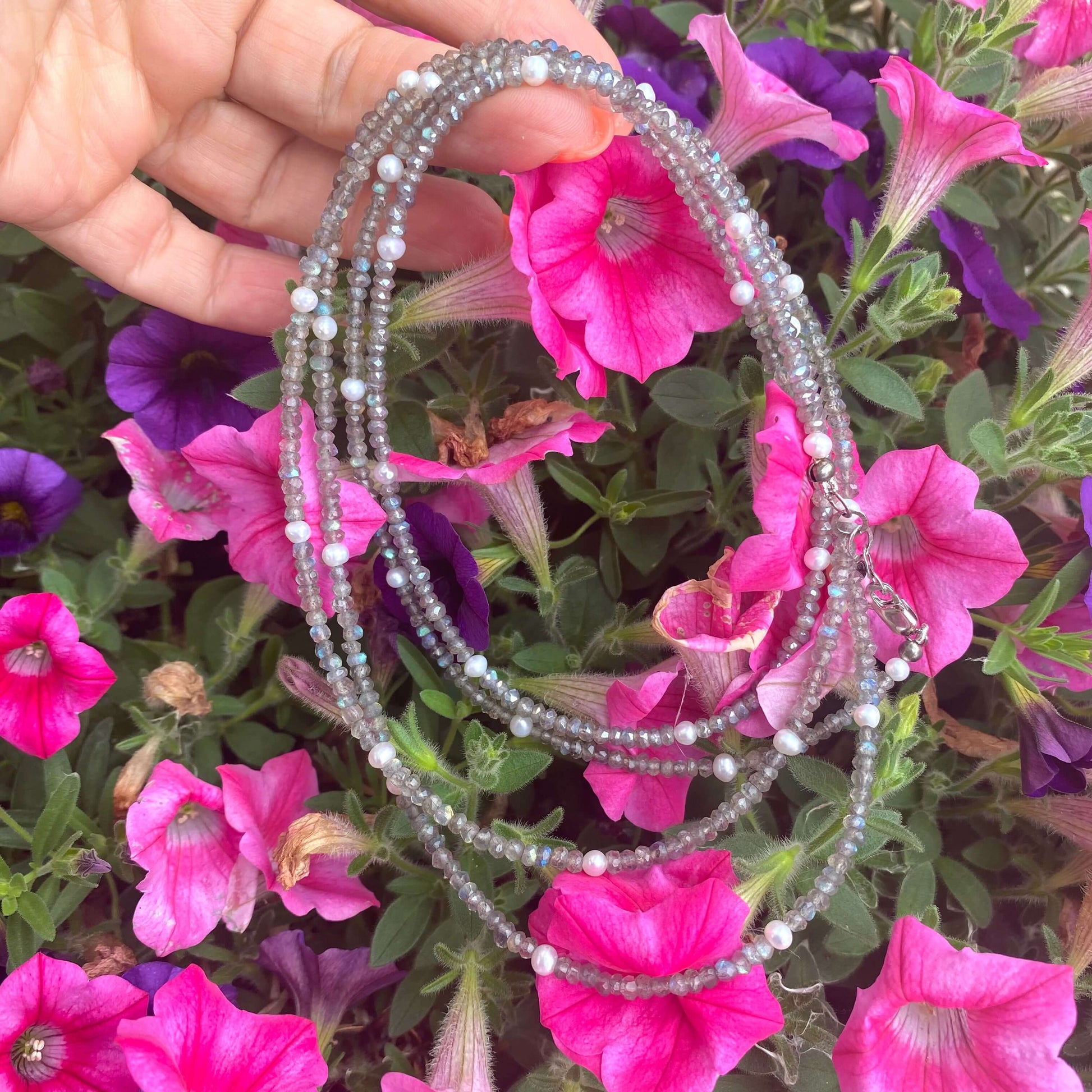 Labradorite freshwater pearl necklace displayed against vibrant pink flowers, showcasing handcrafted long design with shimmering gemstones.