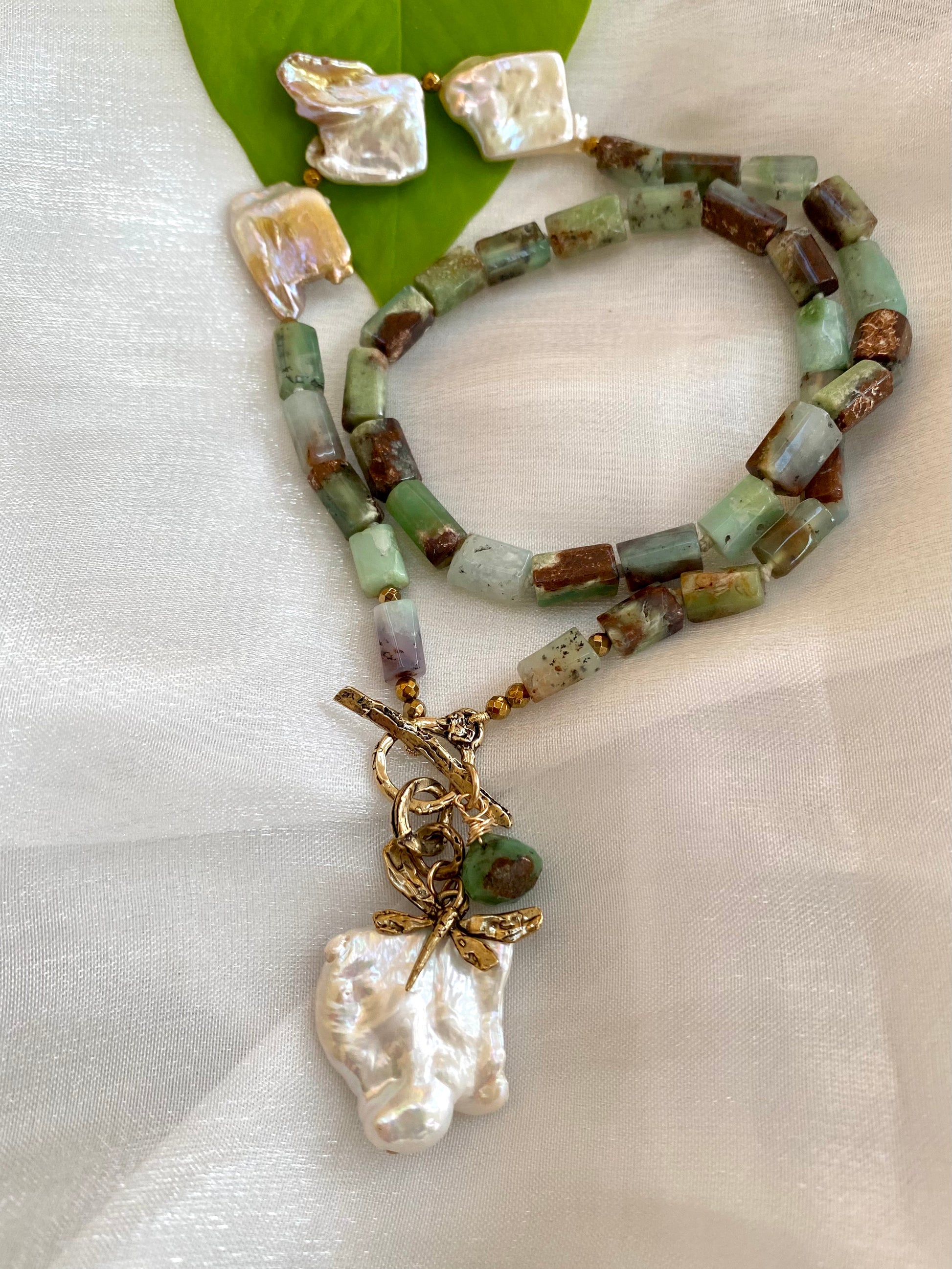 Chrysoprase necklace with dragonfly charm and baroque pearl, showcasing vibrant green gemstones and unique design.
