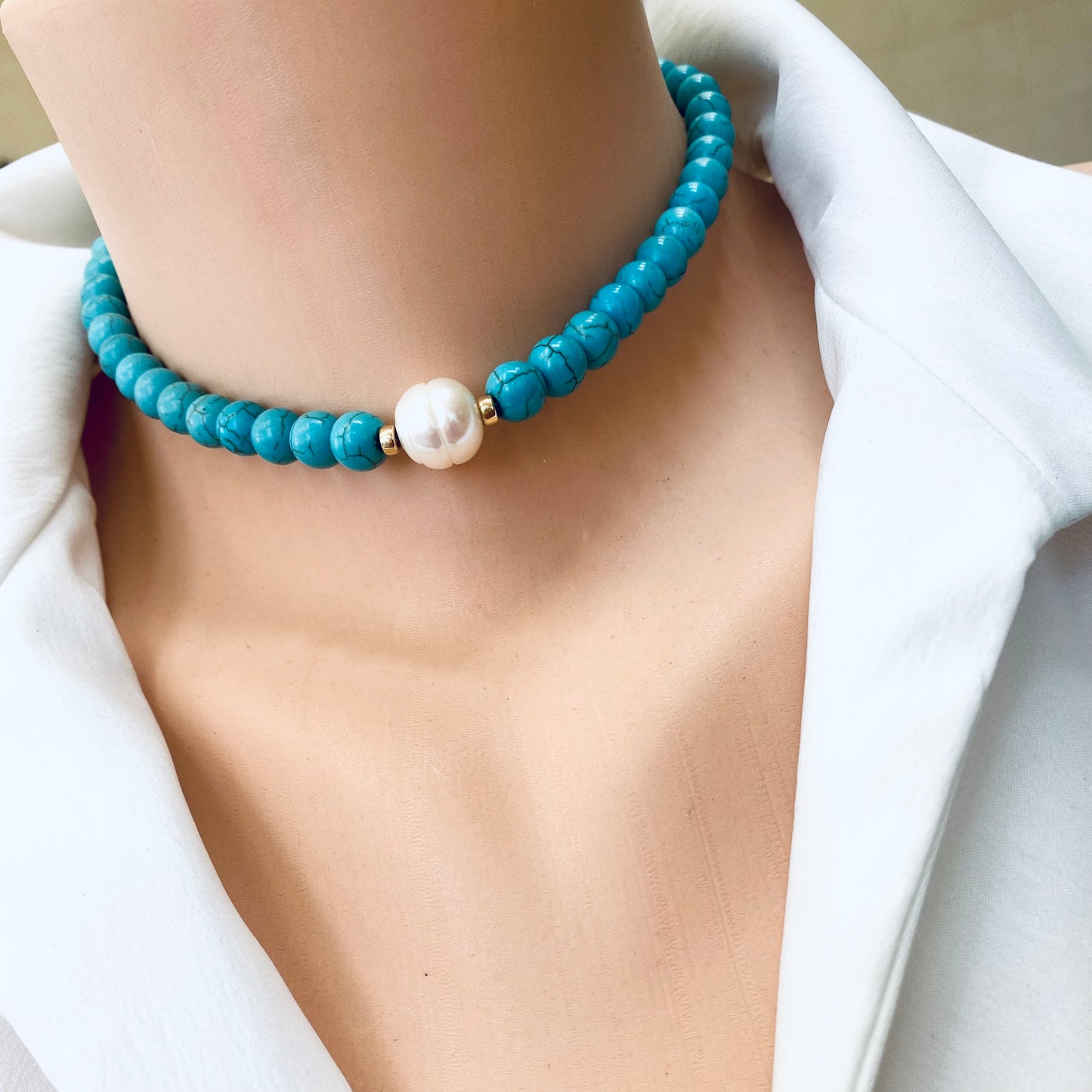 Turquoise howlite pearl choker necklace worn close to the neckline with gold filled details