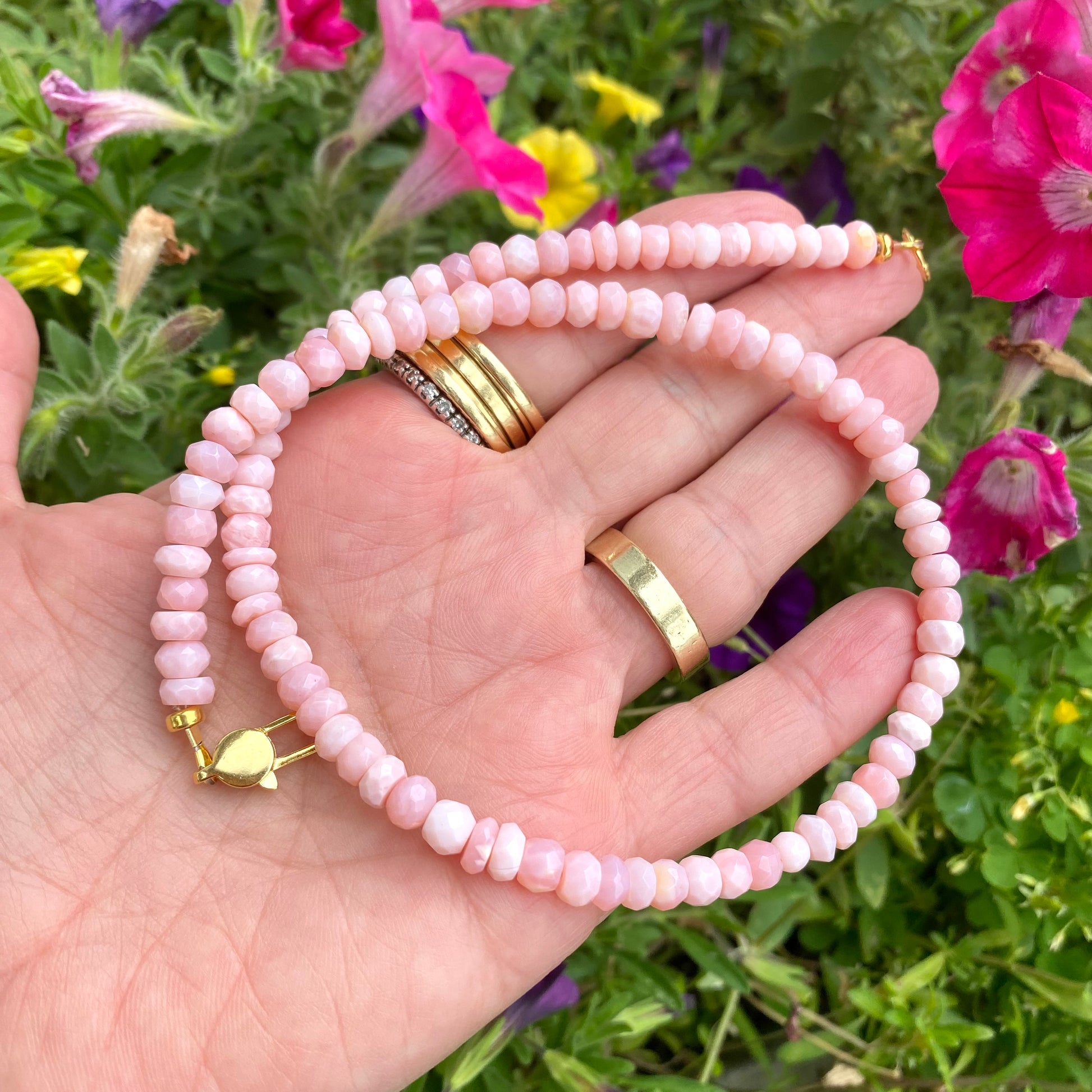 Pink opal short necklace held in hand showing faceted opal beads and gold vermeil clasp