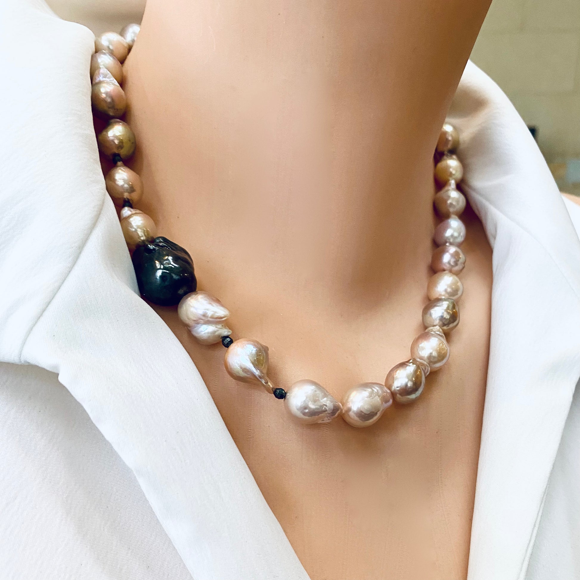Side close-up of pink baroque pearl necklace worn by mannequin, black rhodium silver clasp visible.