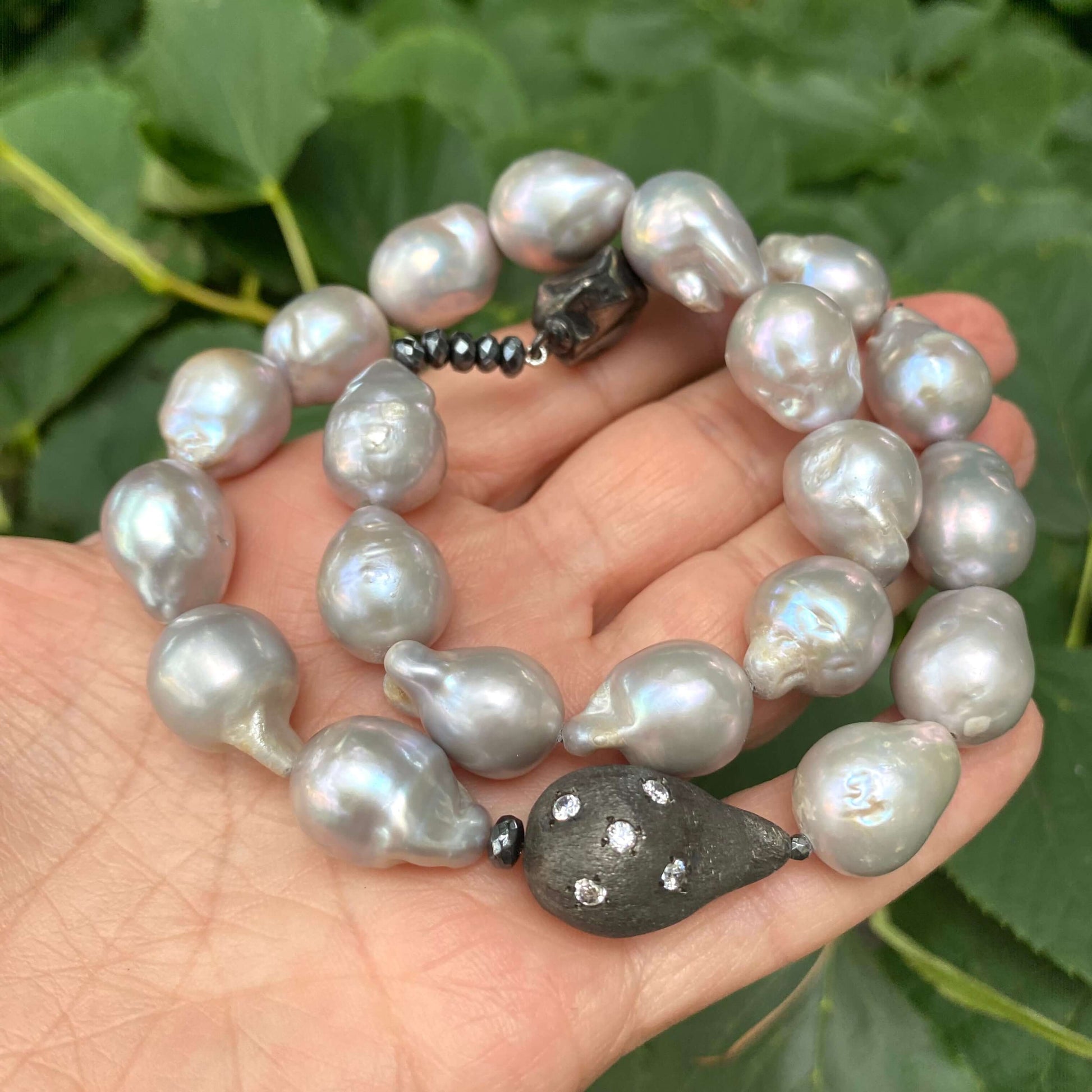Grey Baroque Pearl Choker Necklace held in hand, showcasing unique organic shapes and lustrous grey pearls.