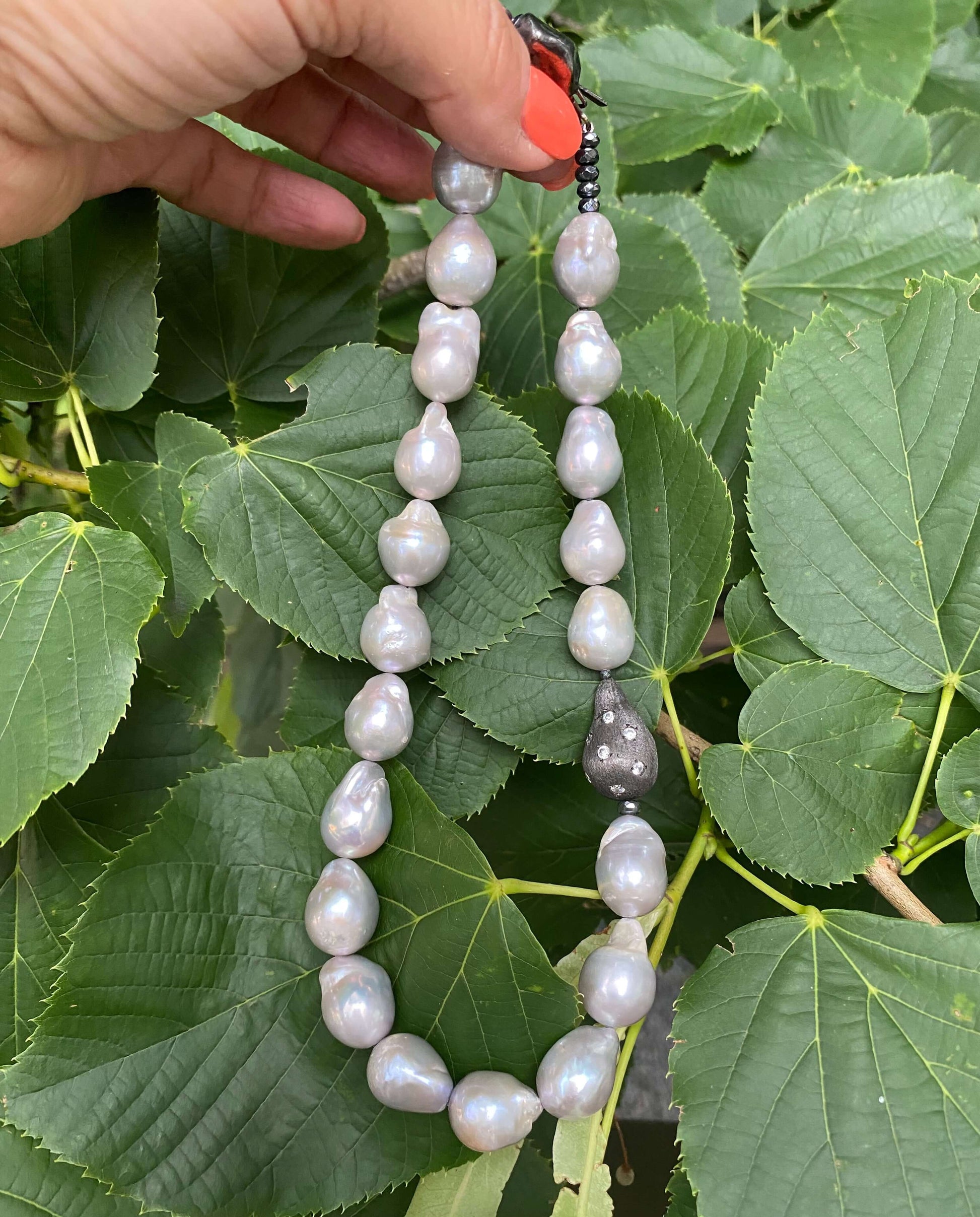 Grey Baroque Pearl Choker Necklace – Baroque-Inspired Statement Piece displayed among lush green leaves.