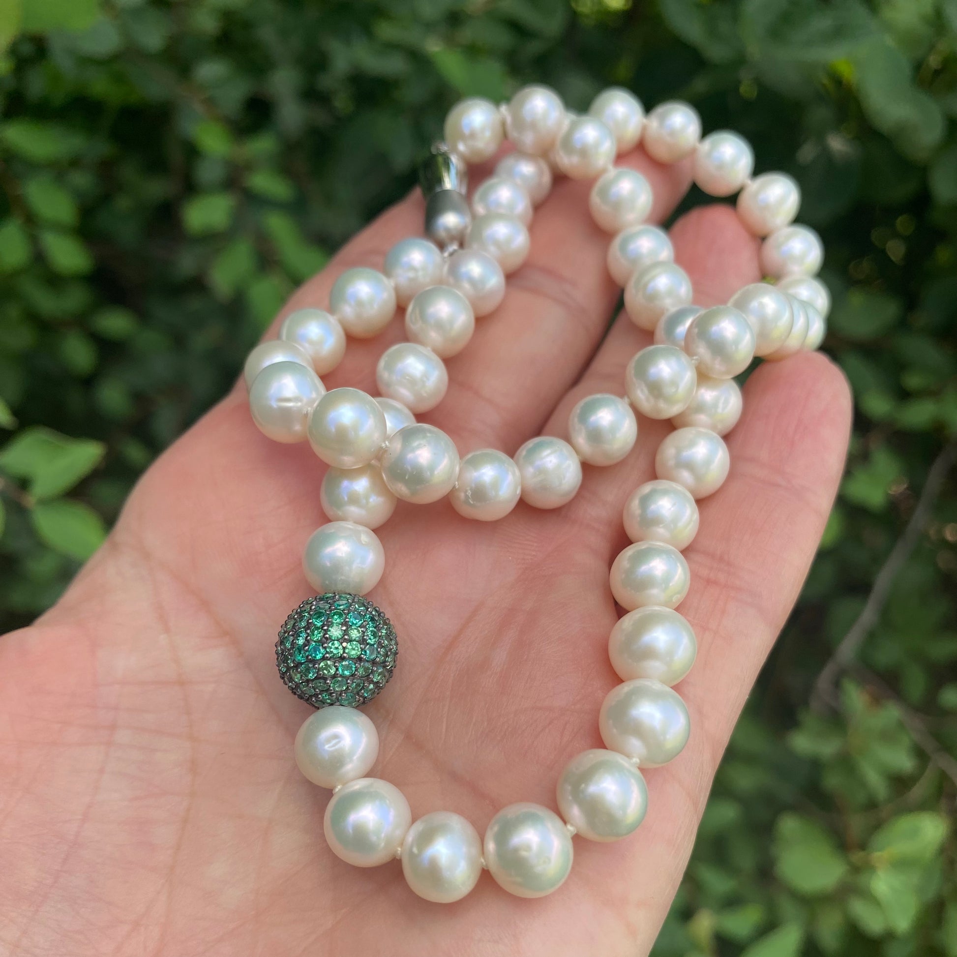 Pearl necklace with green CZ bead, handmade in Canada, showcasing lustrous freshwater pearls and vibrant emerald green detail.