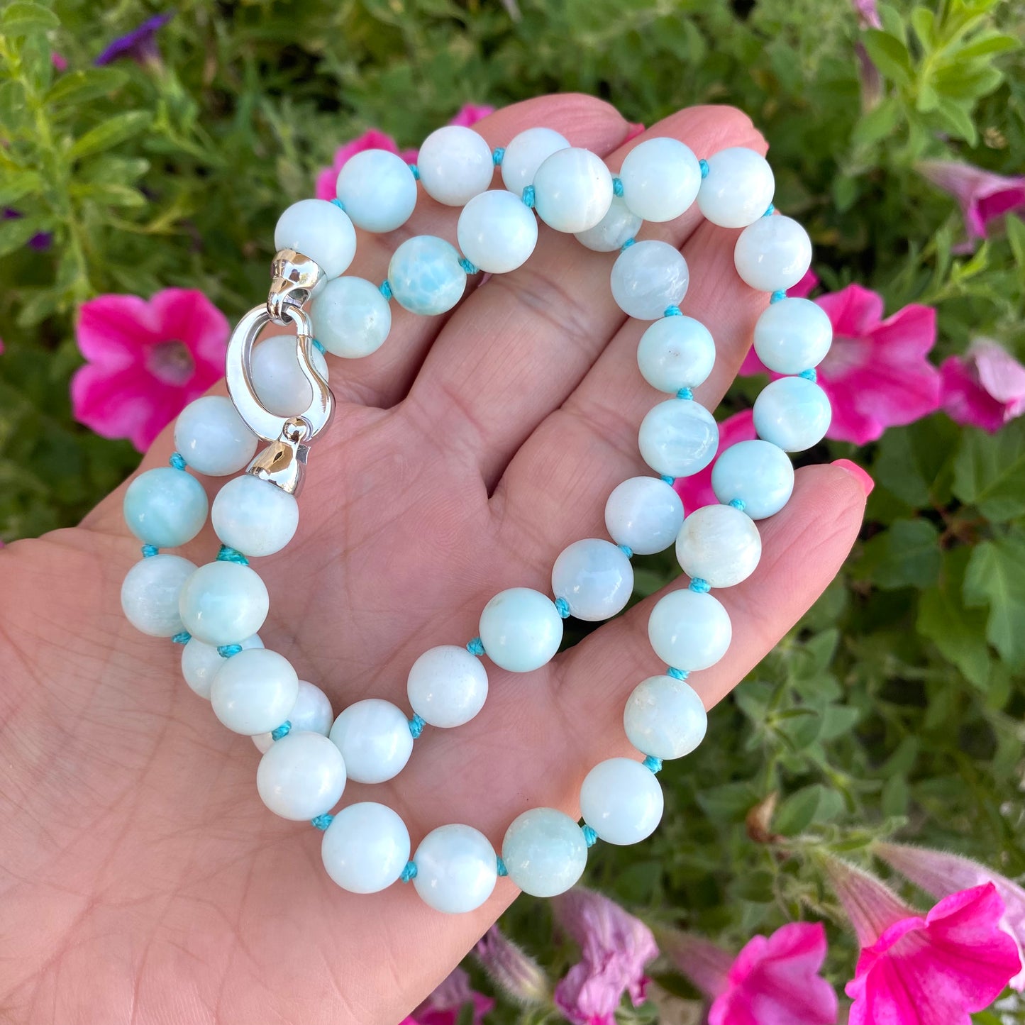 Light blue hemimorphite candy necklace held in hand showing round hemimorphite beads