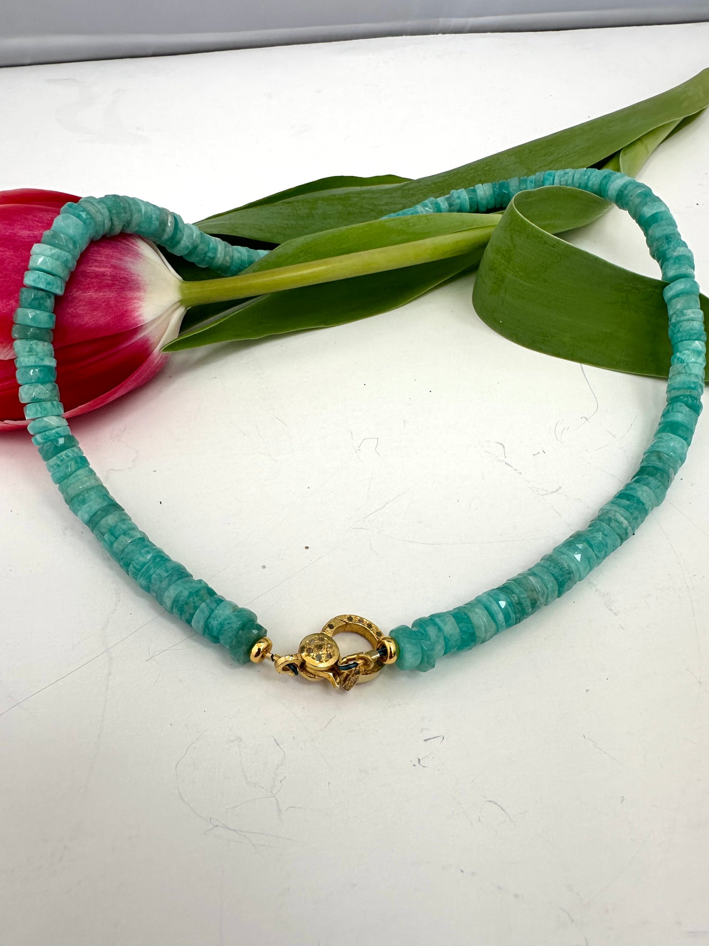 AMAZONITE beaded necklace with a gold clasp on a white surface with tulips.