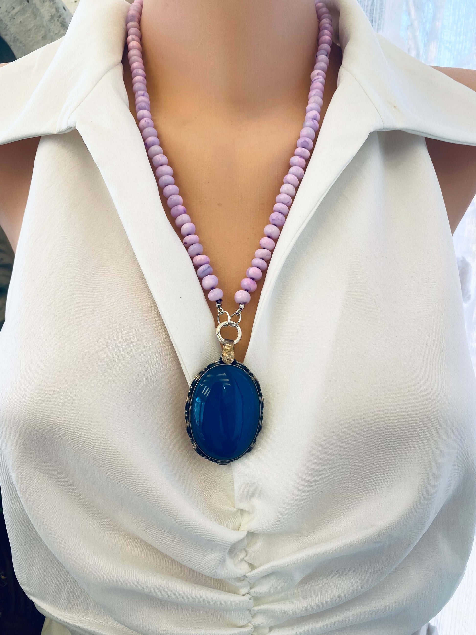 Vintage blue agate pendant in oxidized sterling silver worn on a lilac bead necklace.