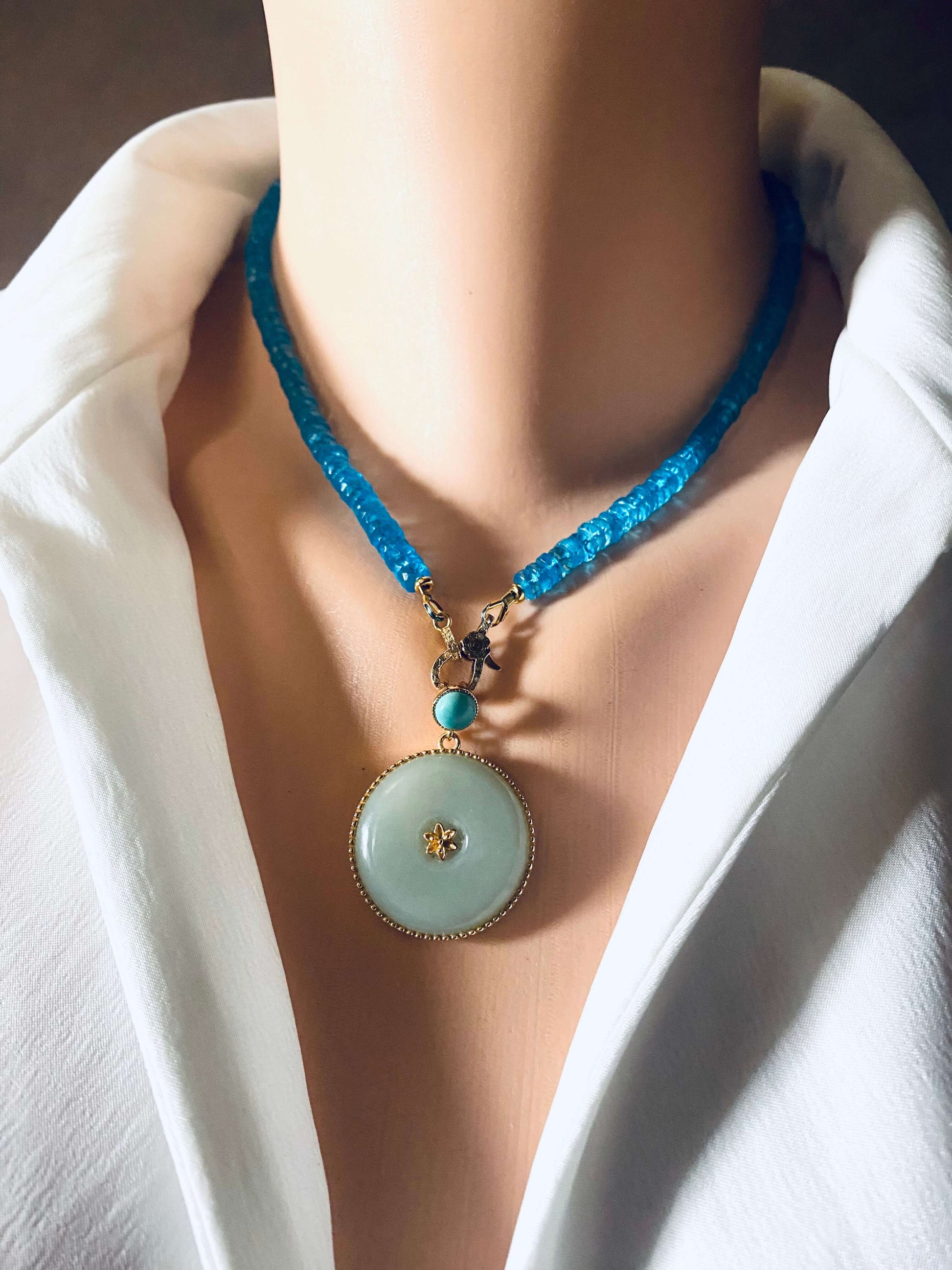Hotan jade pendant with turquoise accent in gold vermeil, displayed on a mannequin wearing a blue beaded necklace.