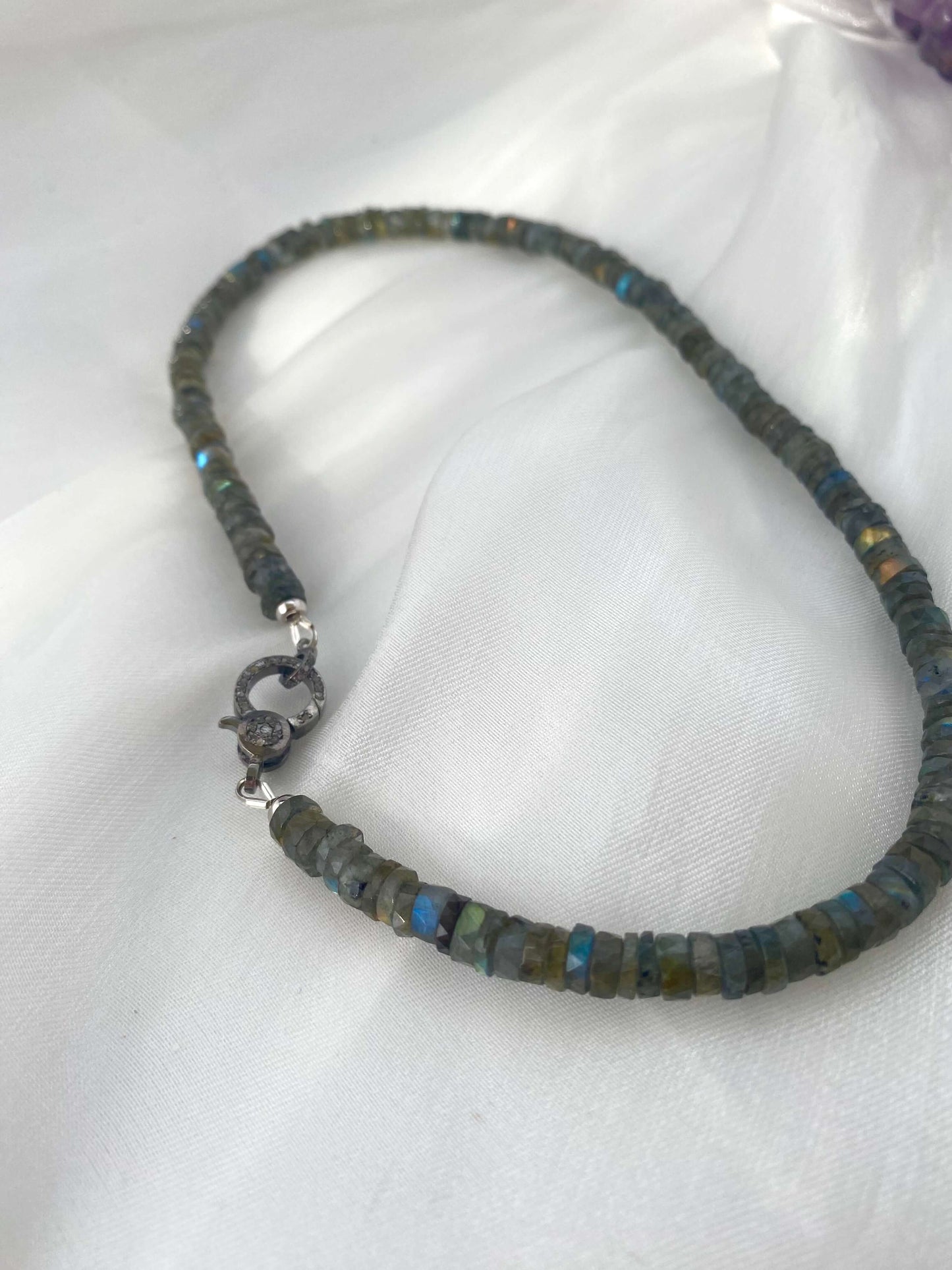 Labradorite beaded necklace featuring faceted heishi beads and oxidized silver pavé clasp on a soft background.