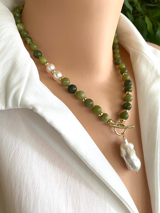 Necklace with green beads and a large white pearl on a mannequin wearing a white shirt.