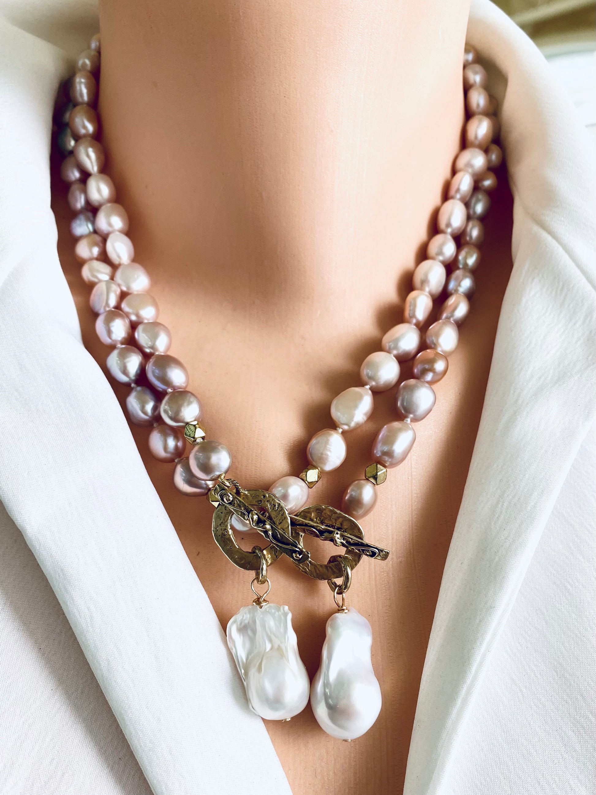 Two pink pearl necklaces with baroque pendants worn on mannequin, frontal view