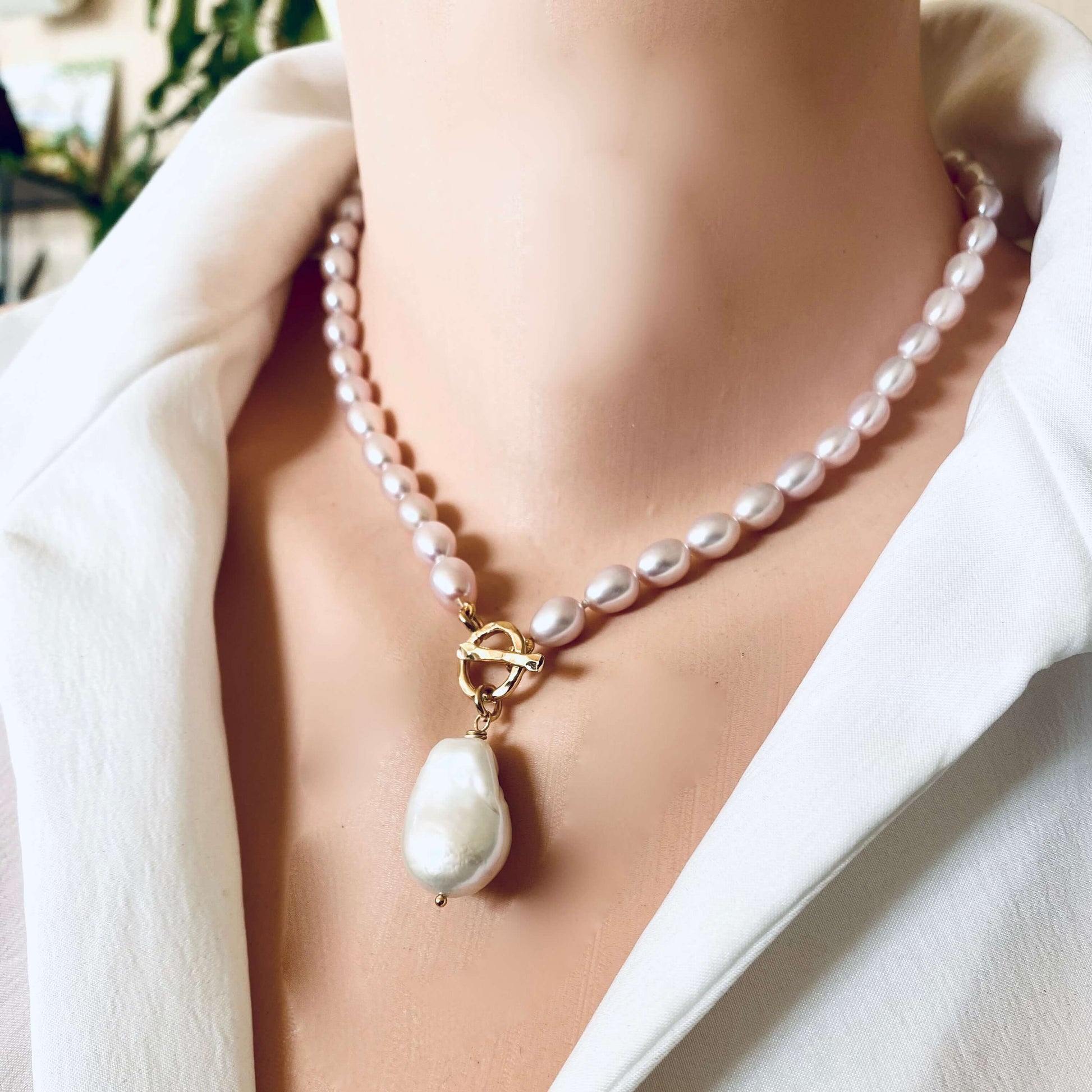 Pink pearl toggle necklace with baroque pearl worn on model sitting elegantly at the collarbone
