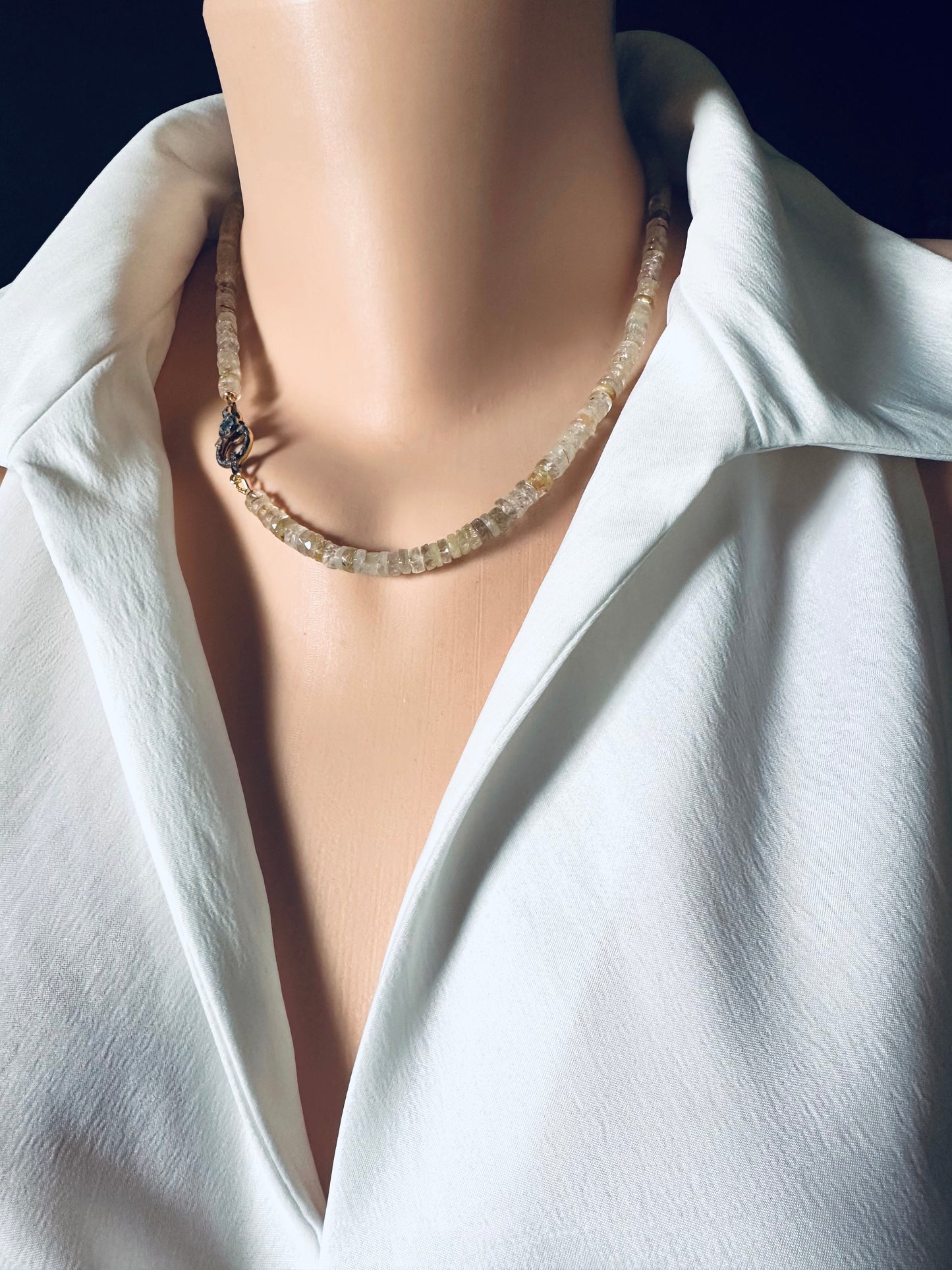 Necklace on a mannequin with a white shirt against a dark background