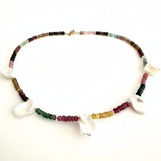 A beaded necklace featuring small multicolored gemstone beads and several white shell charms, displayed on a plain white background.