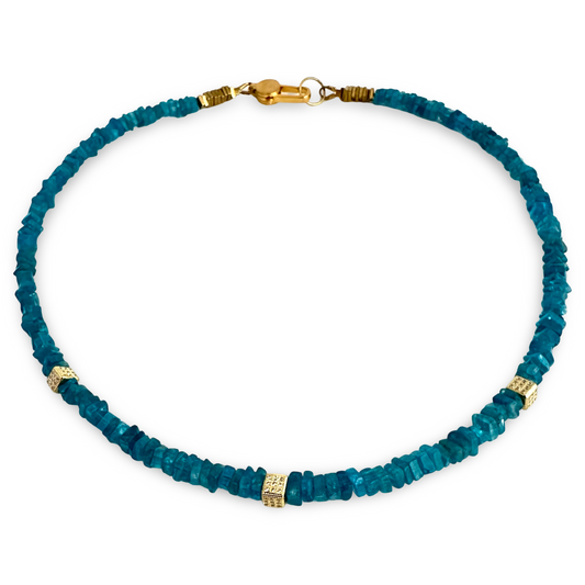 A beaded necklace made of faceted teal-blue gemstone chips with small gold spacer beads and a gold clasp, shown on a plain white background.