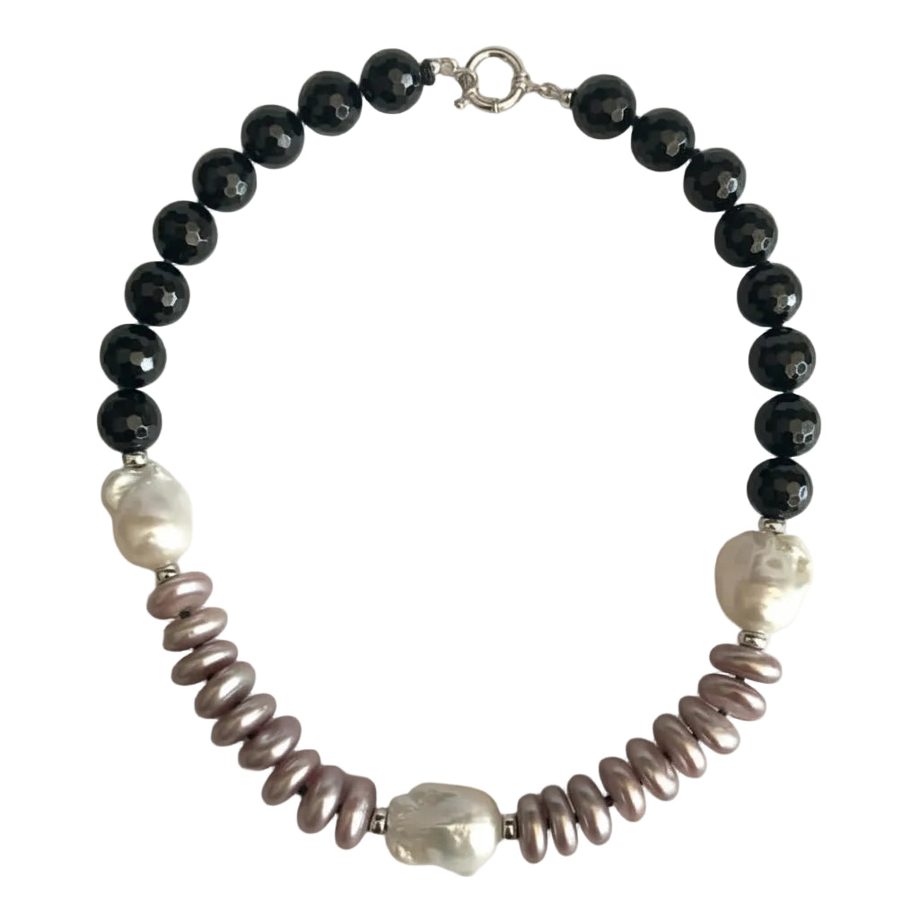 A beaded necklace featuring black faceted round beads, irregular white pearl-like beads, and textured mauve-pink spiny oyster shell beads, displayed on a light off-white background.