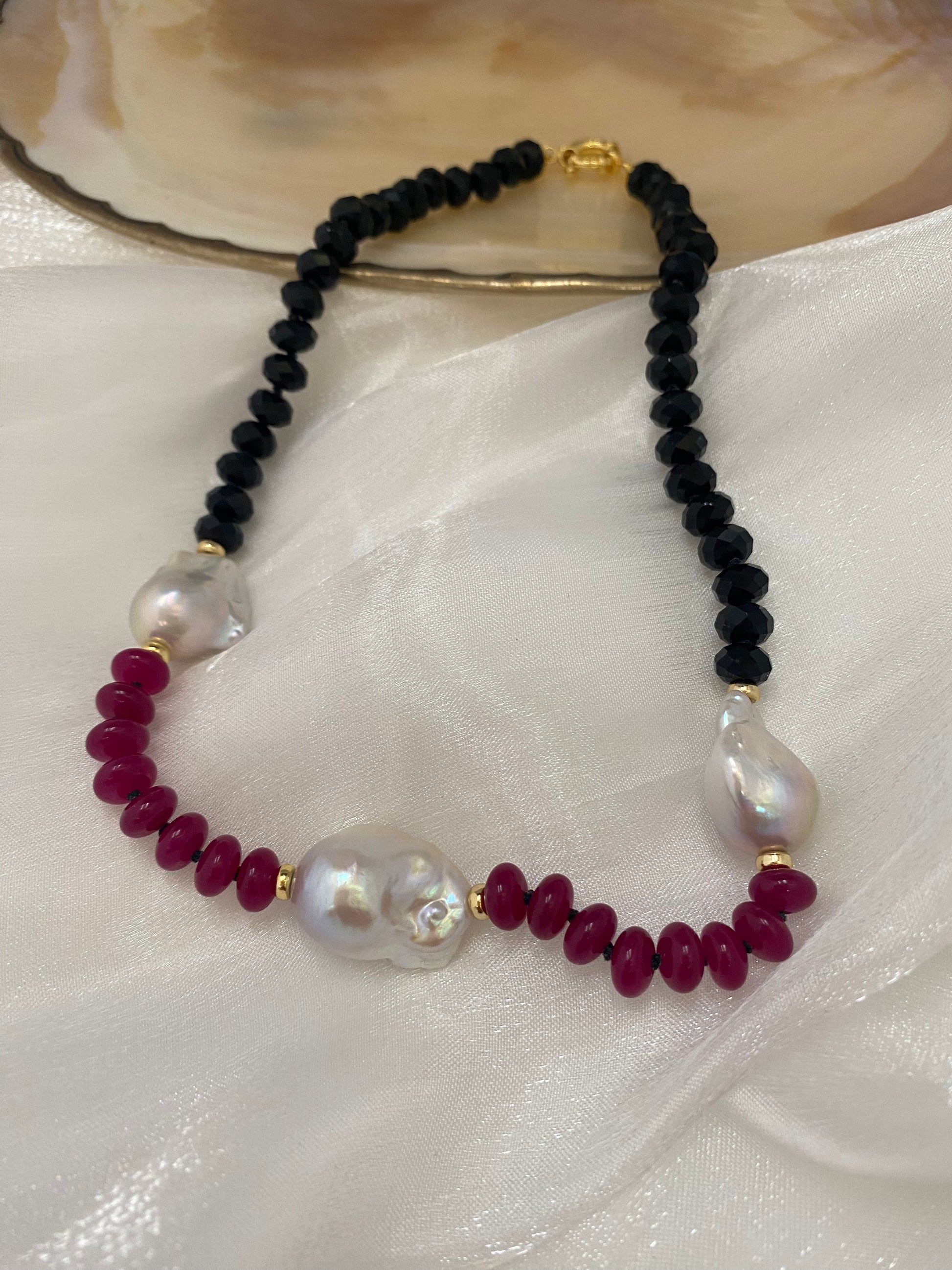 Necklace with black, red, and white beads on a white fabric background