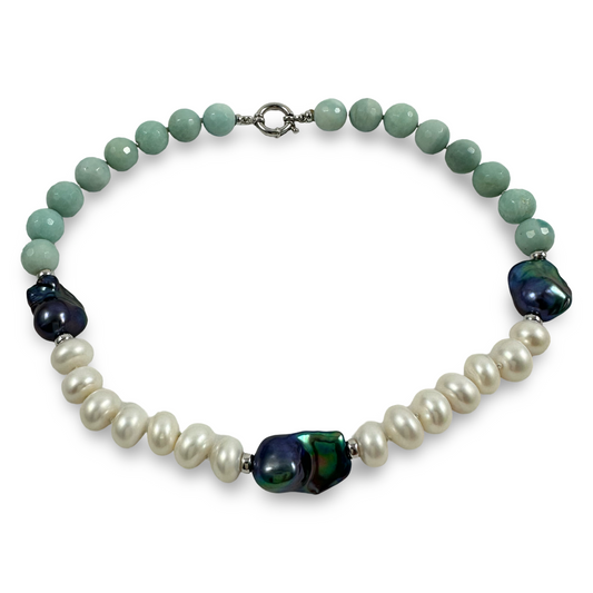 A beaded necklace featuring light green faceted beads, white baroque pearls, and dark iridescent cabochon beads, completed with a silver-toned clasp on a white background.